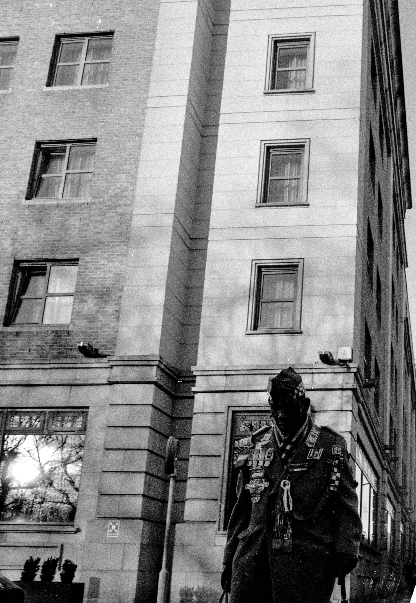 A man in uniform walks by a brick and stone building, Angel
