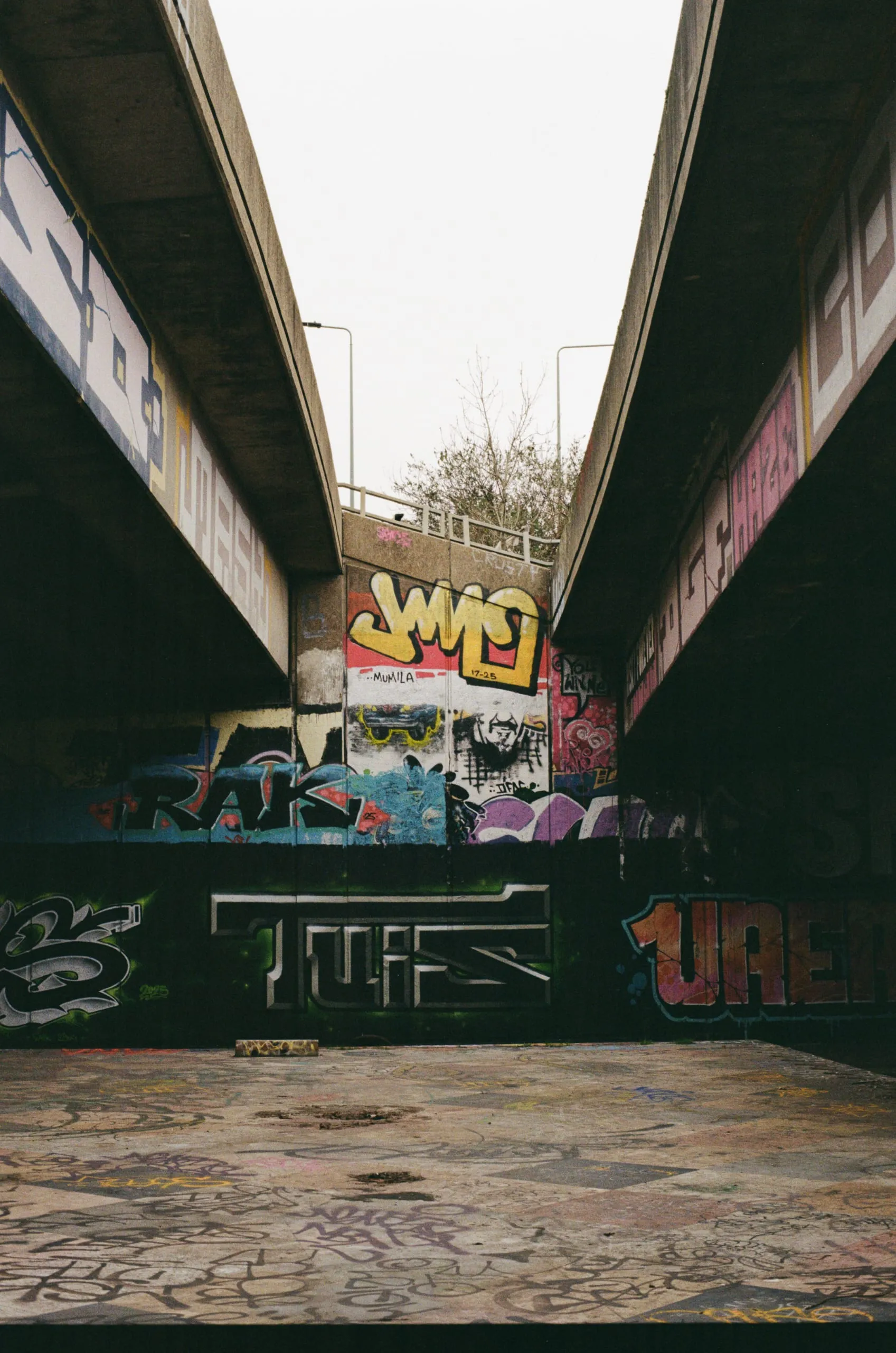 Graffiti-covered walls and pillars beneath a road underpass, London