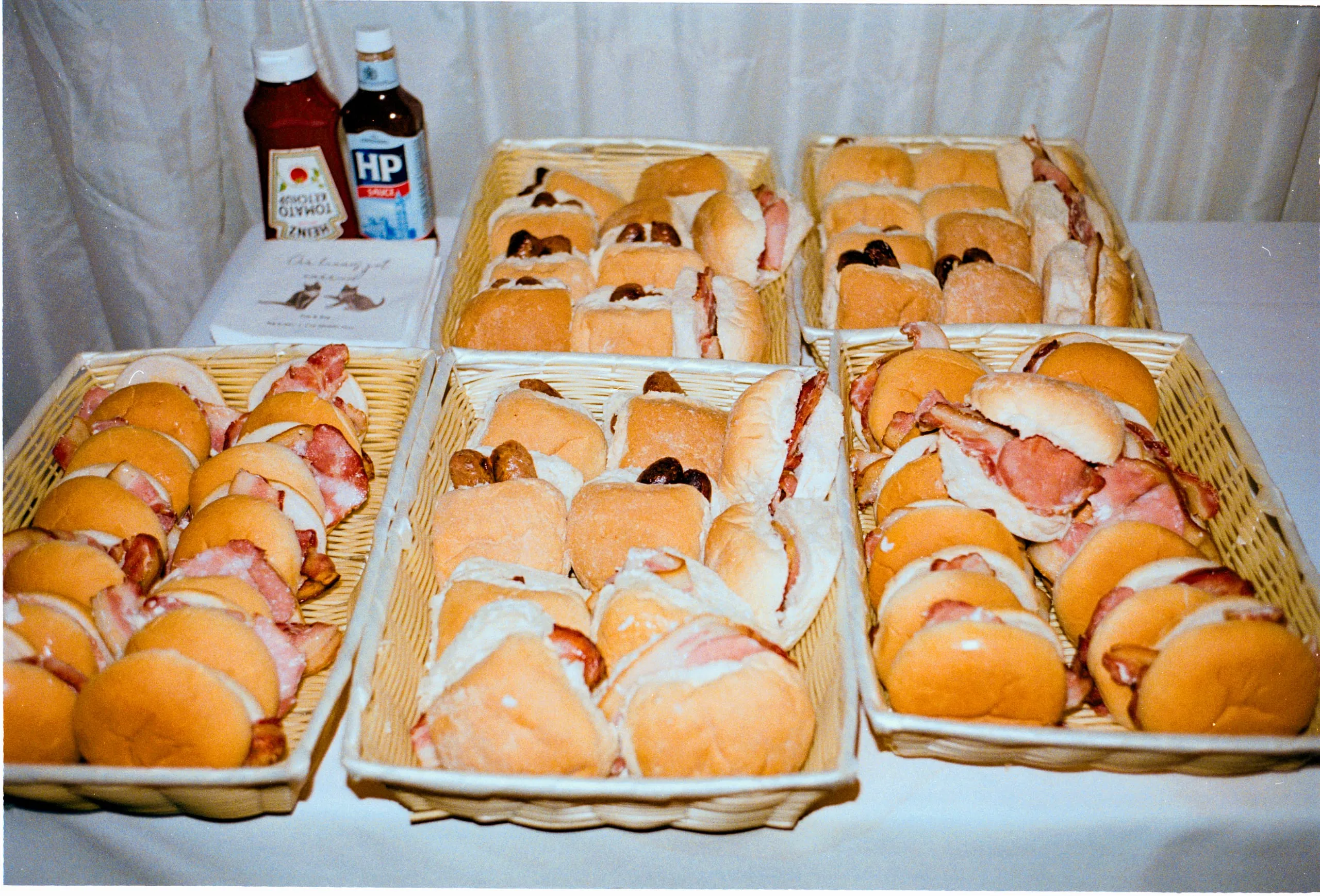 Trays of bacon rolls laid out with ketchup and brown sauce at wedding reception
