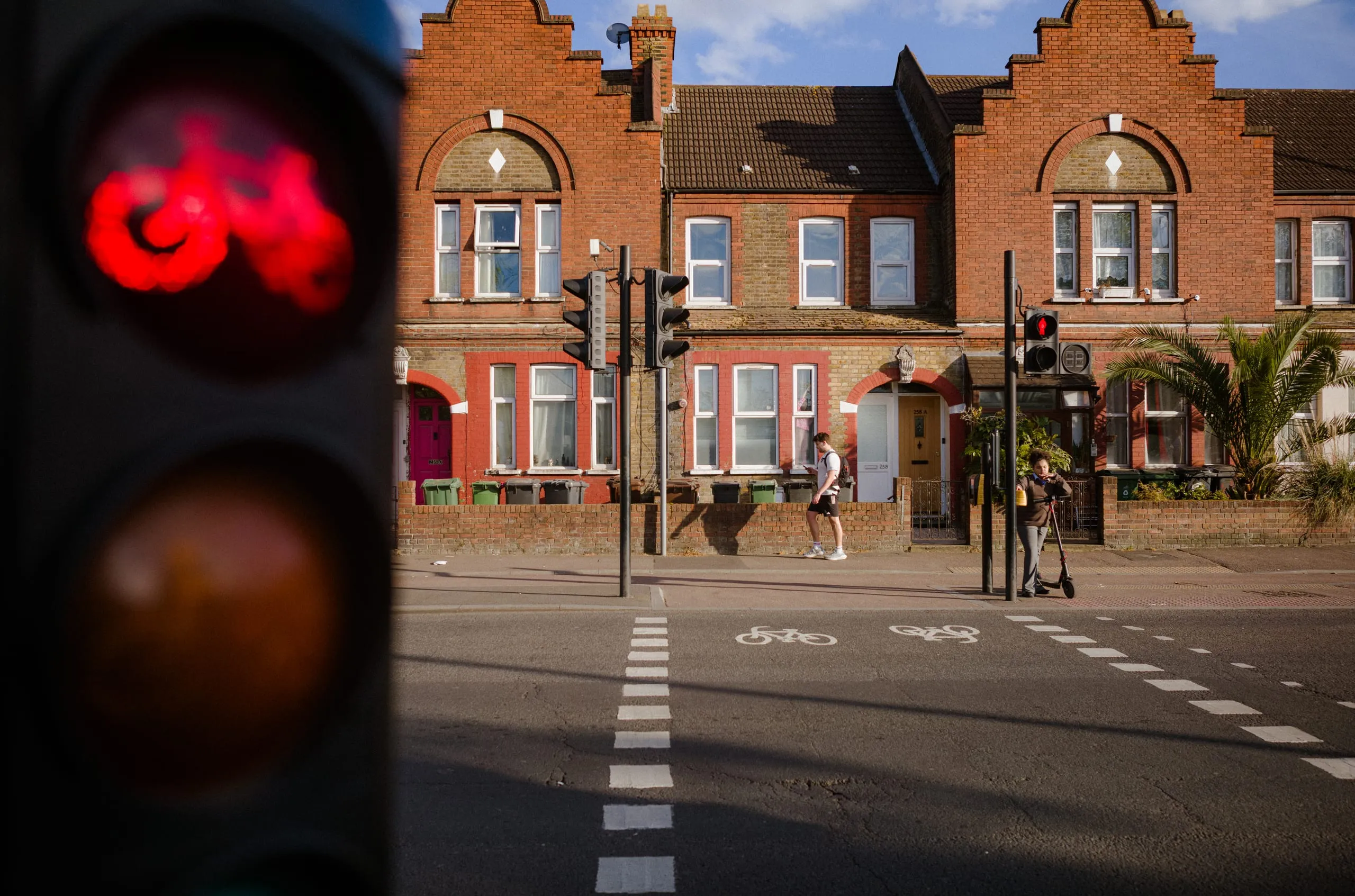 A cyclist crosses at a junction with a red bike traffic light, Lea Bridge Road