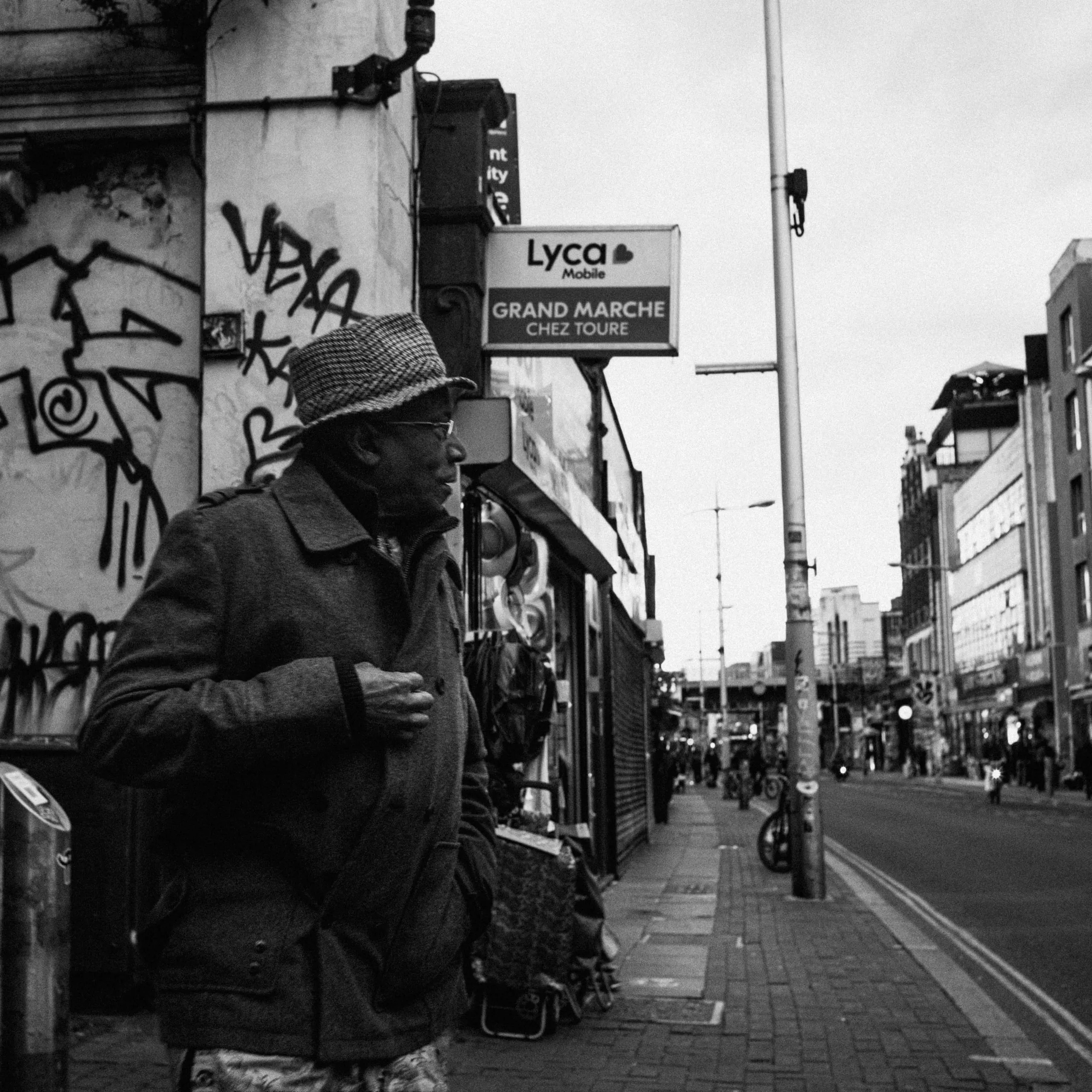 A man in a hat walks down Rye Lane