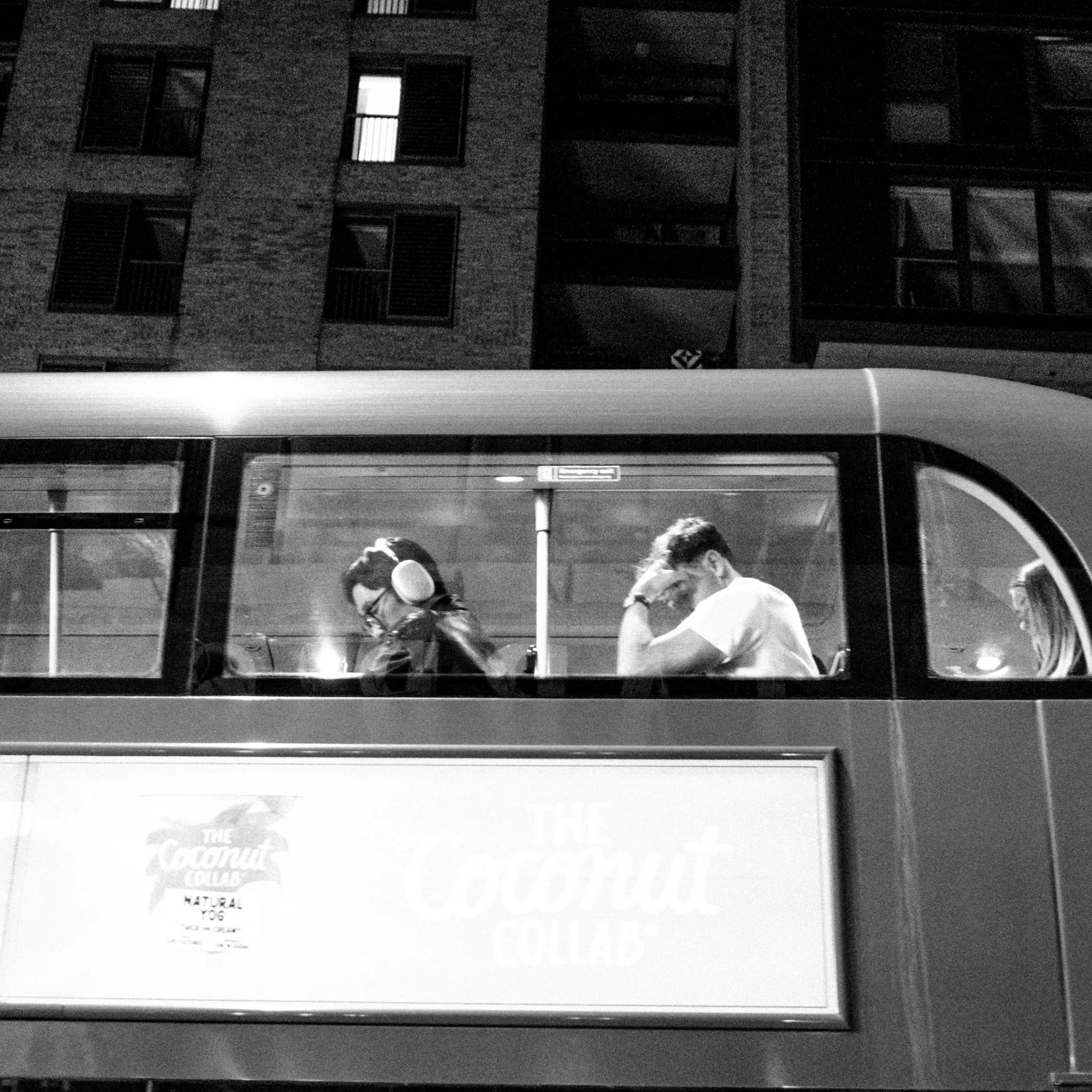 Passengers sit aboard a double-decker bus at night, London