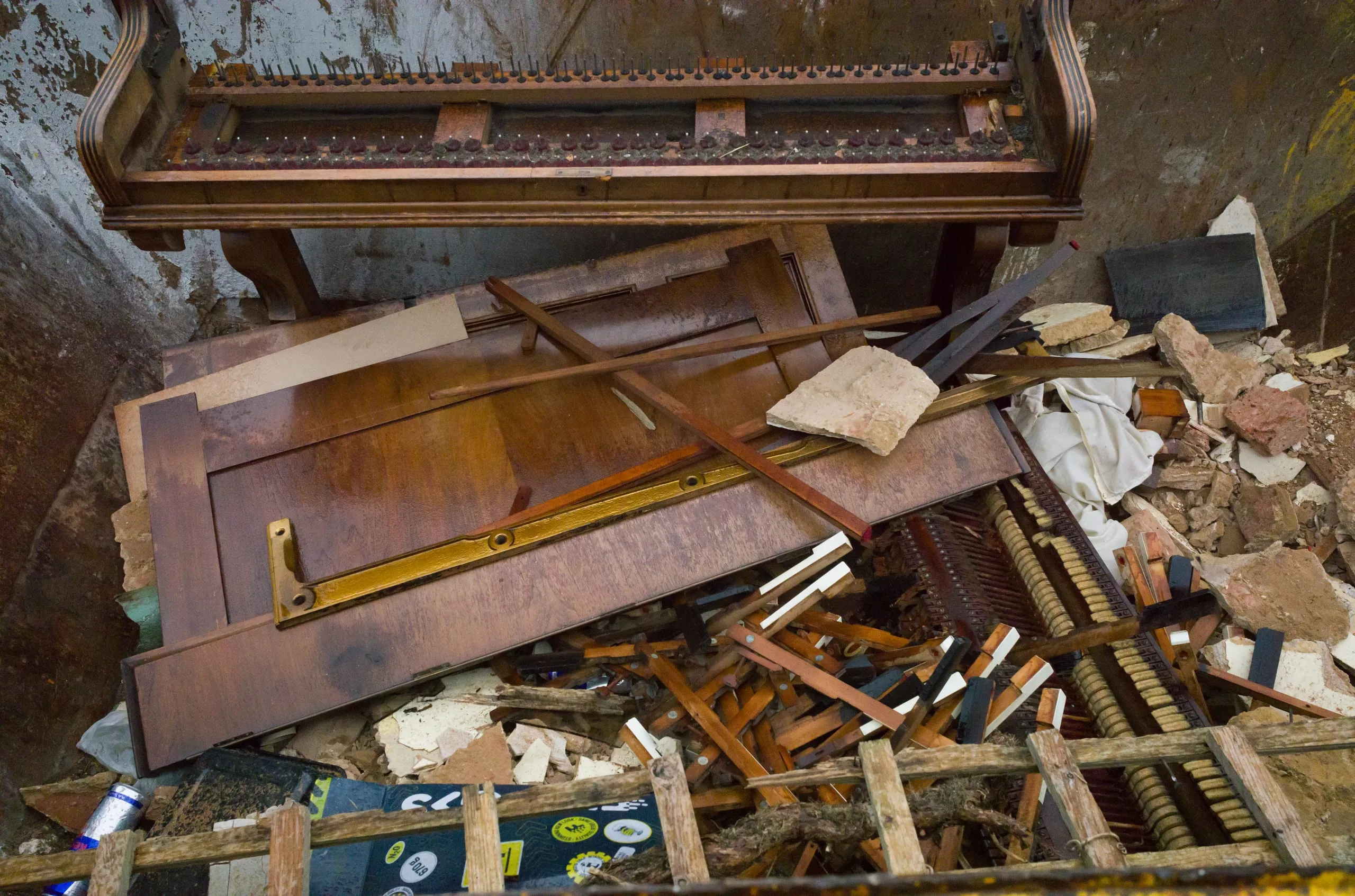 A broken piano waits collection in a skip after a house clearing