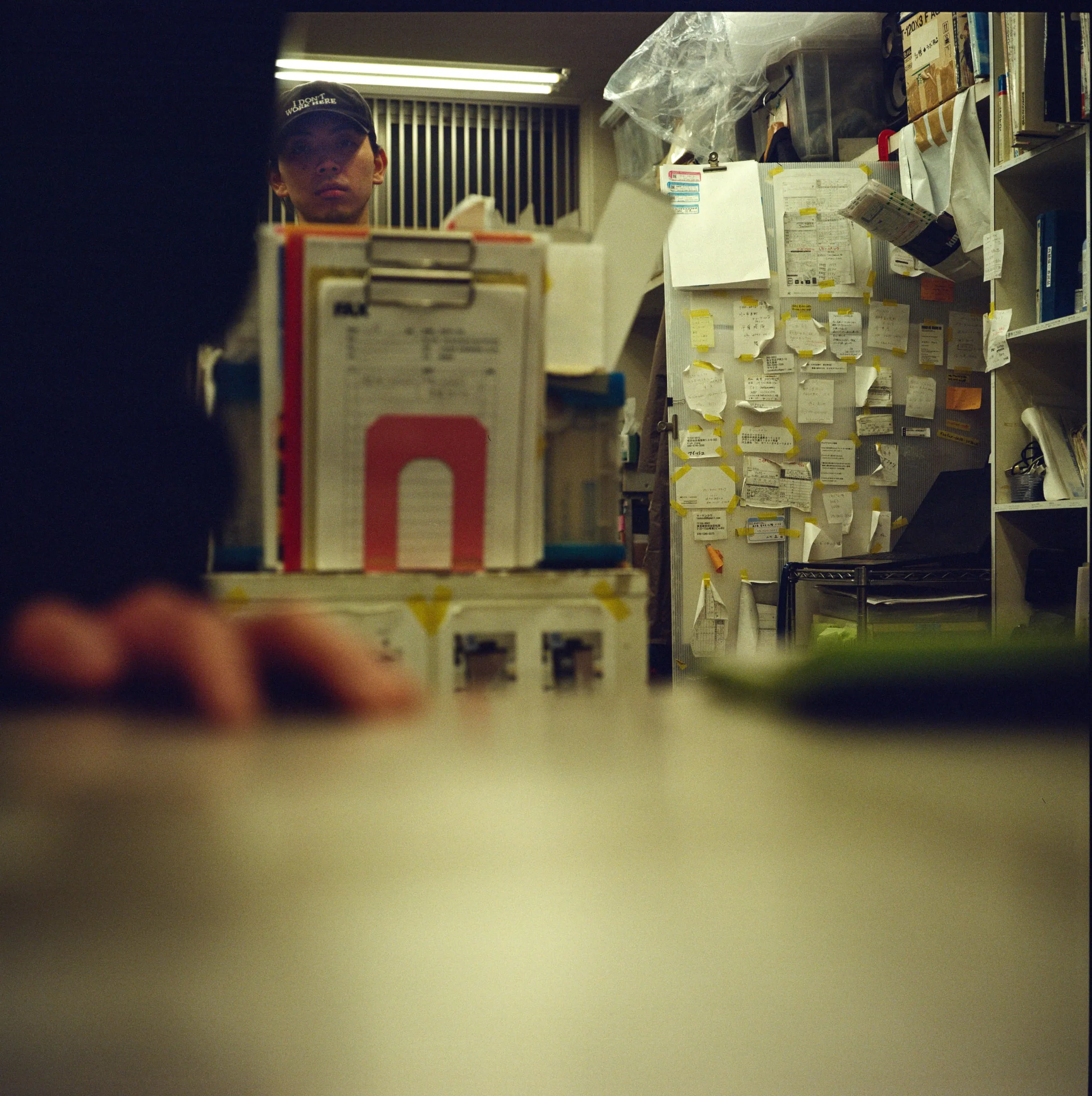 A worker in a cap behind a cluttered counter