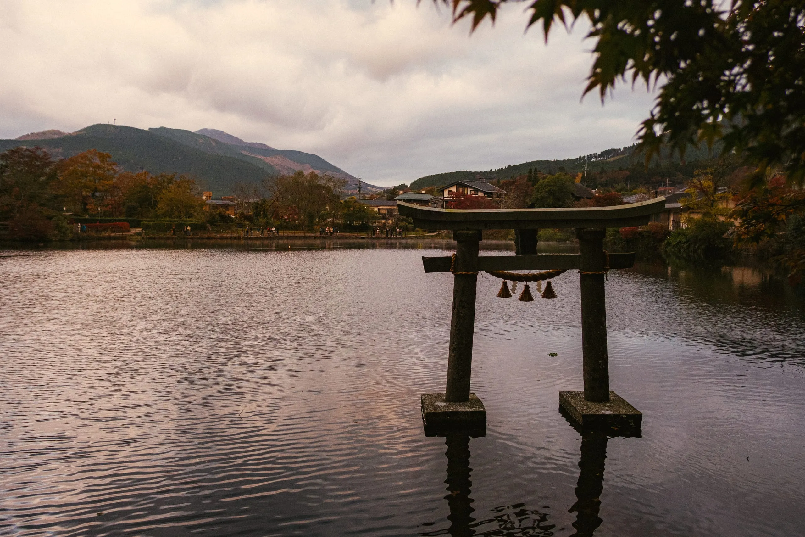 A torii gate standing in a lake below the hills