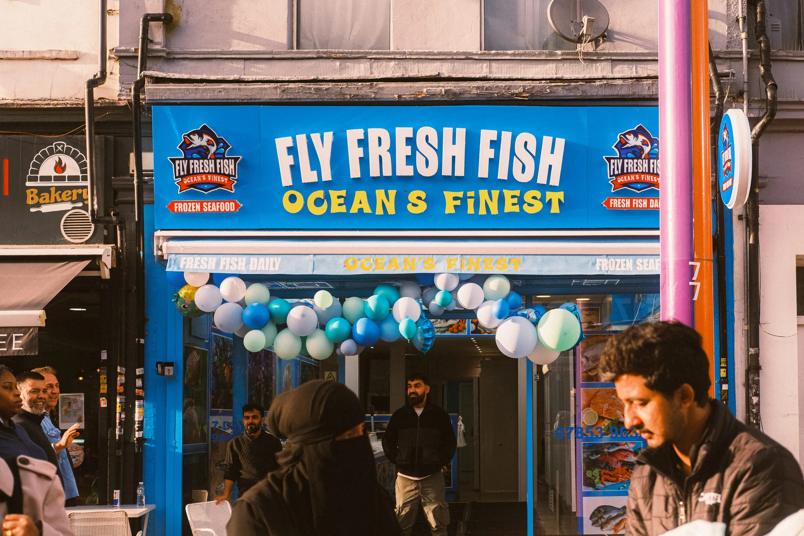 Men gather outside the Fly Fresh Fish shop on its opening day, Walthamstow High Street Market