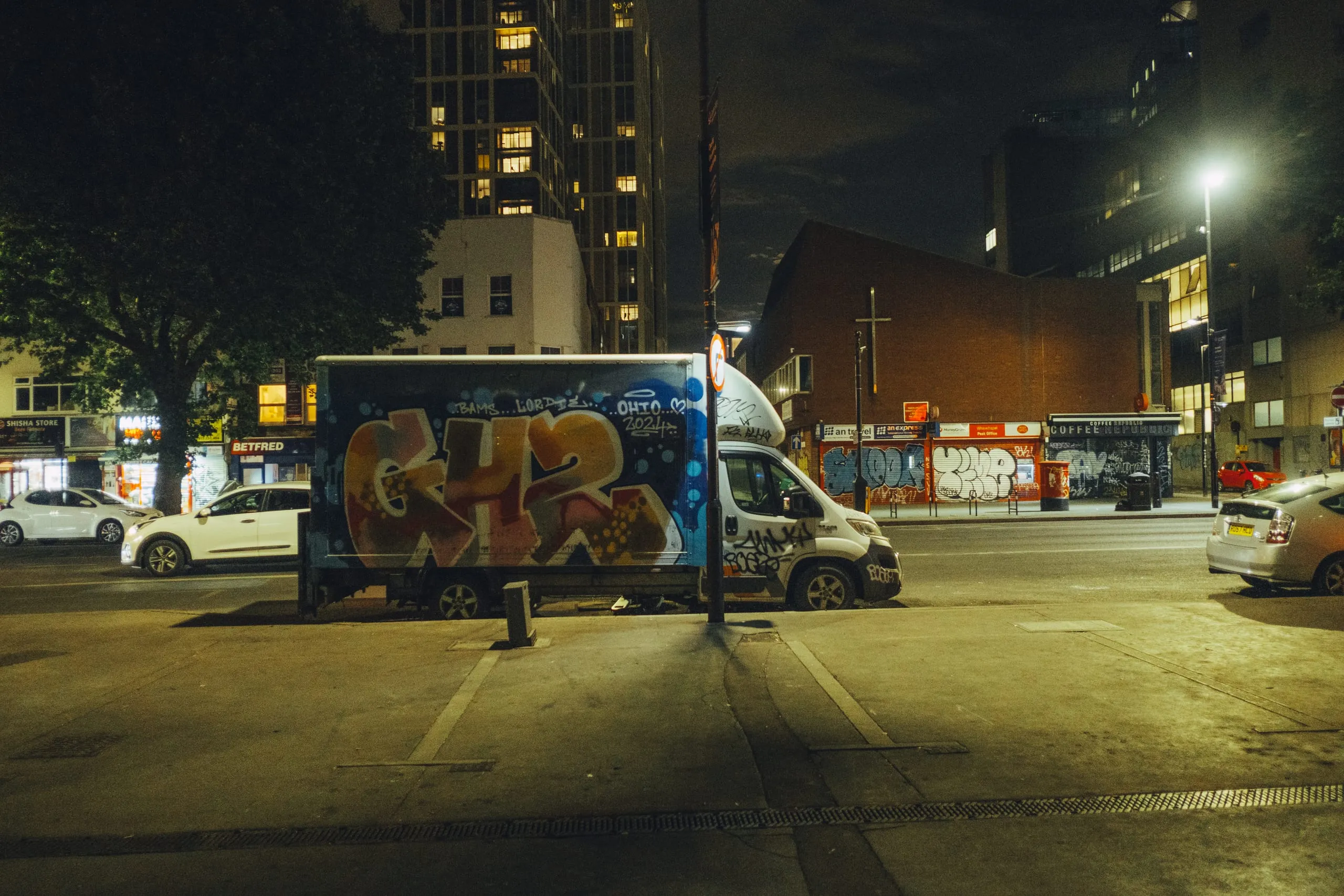 A graffiti-covered van parked on a street corner at night