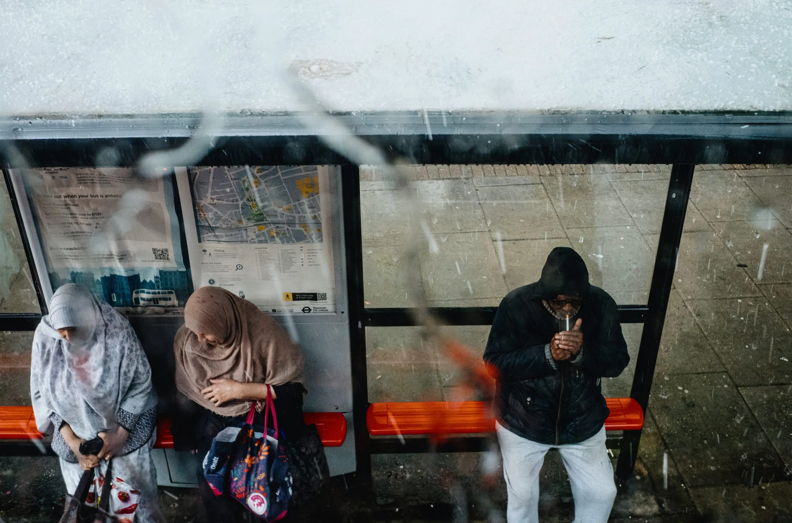 A man lights a cigarette while waiting for the bus, Clapton, 2026