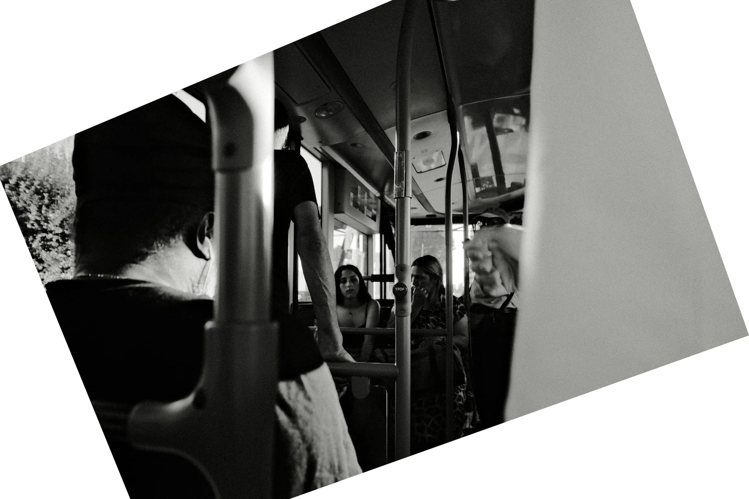 Passengers seated on a bus seen through the handrails