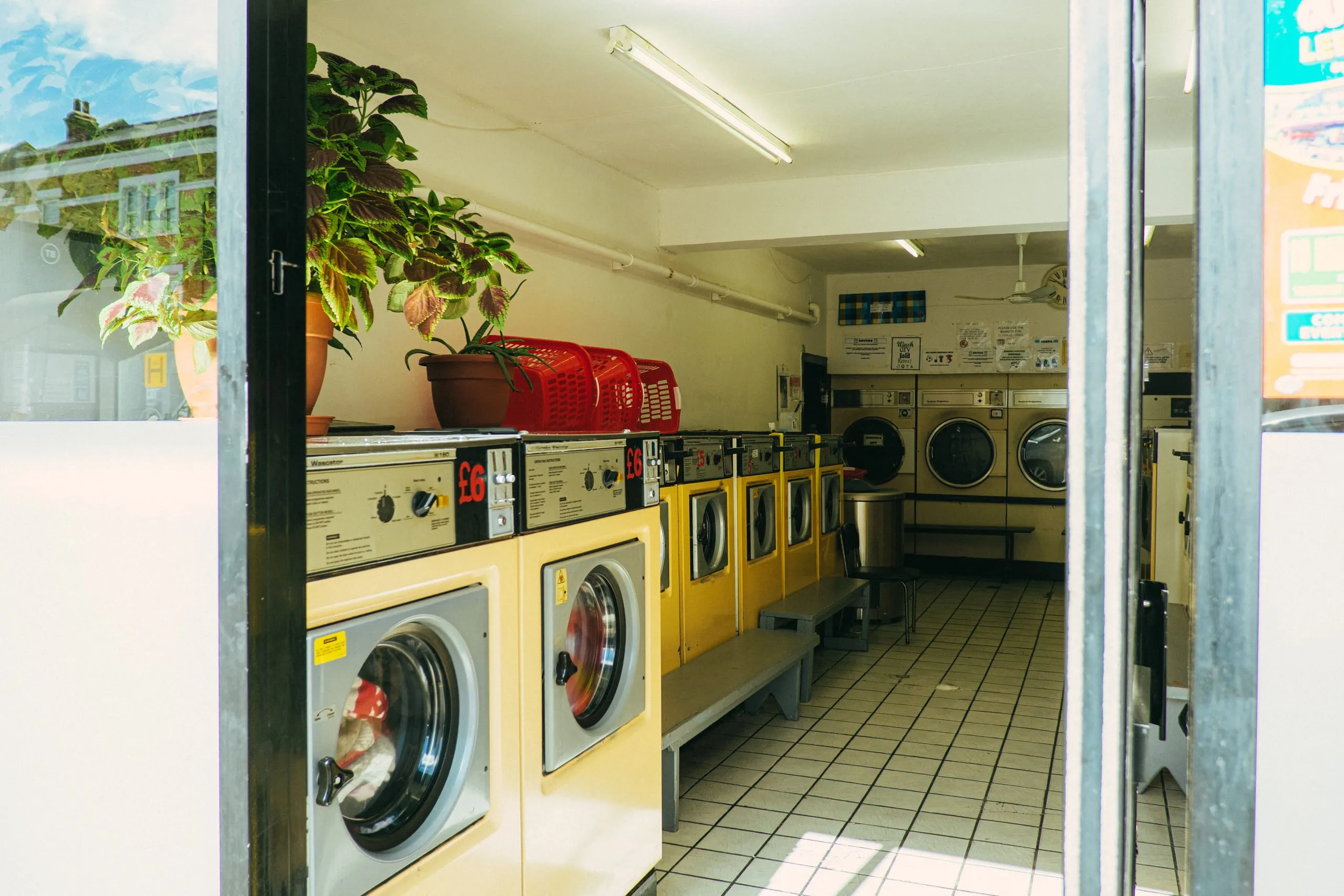 A launderette with rows of washing machines seen through the open door, Lea Bridge Road