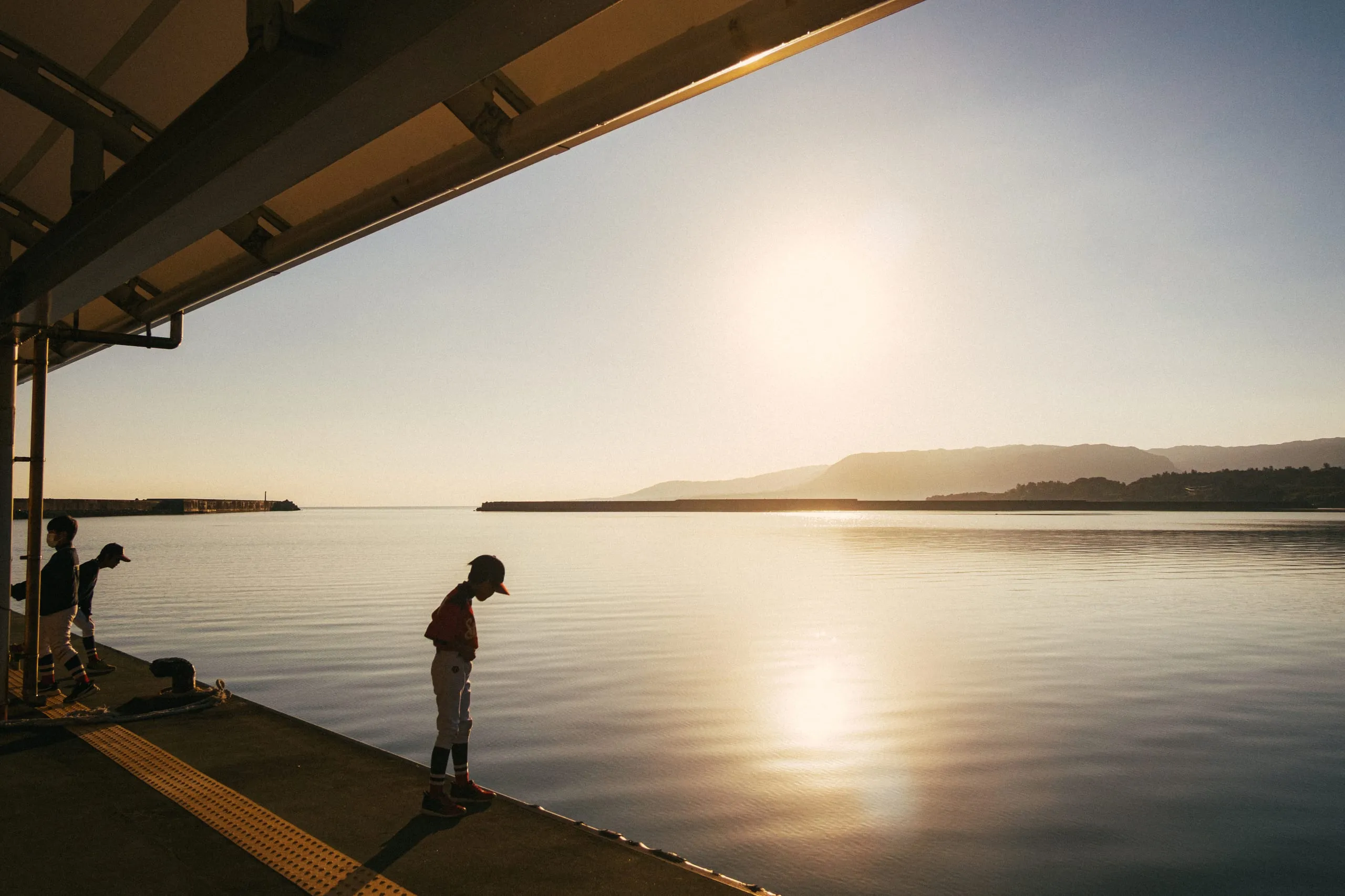 A child baseball team waits for the ferry to Ishigaki at sunrise