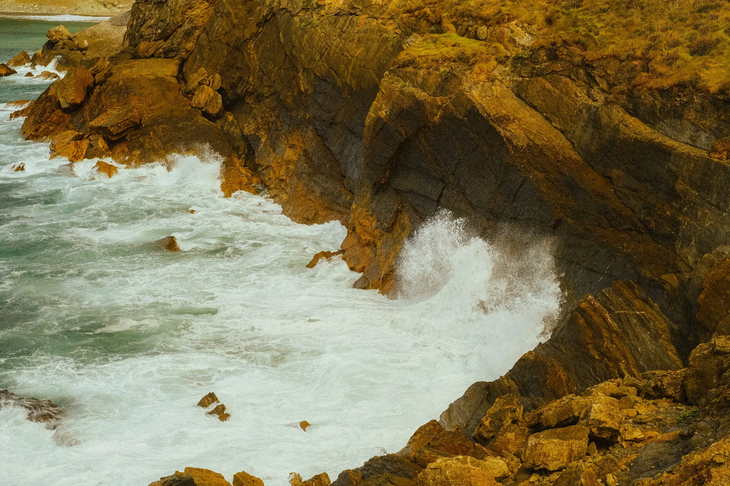 Waves break against the base of a rocky cliff, Verdicio