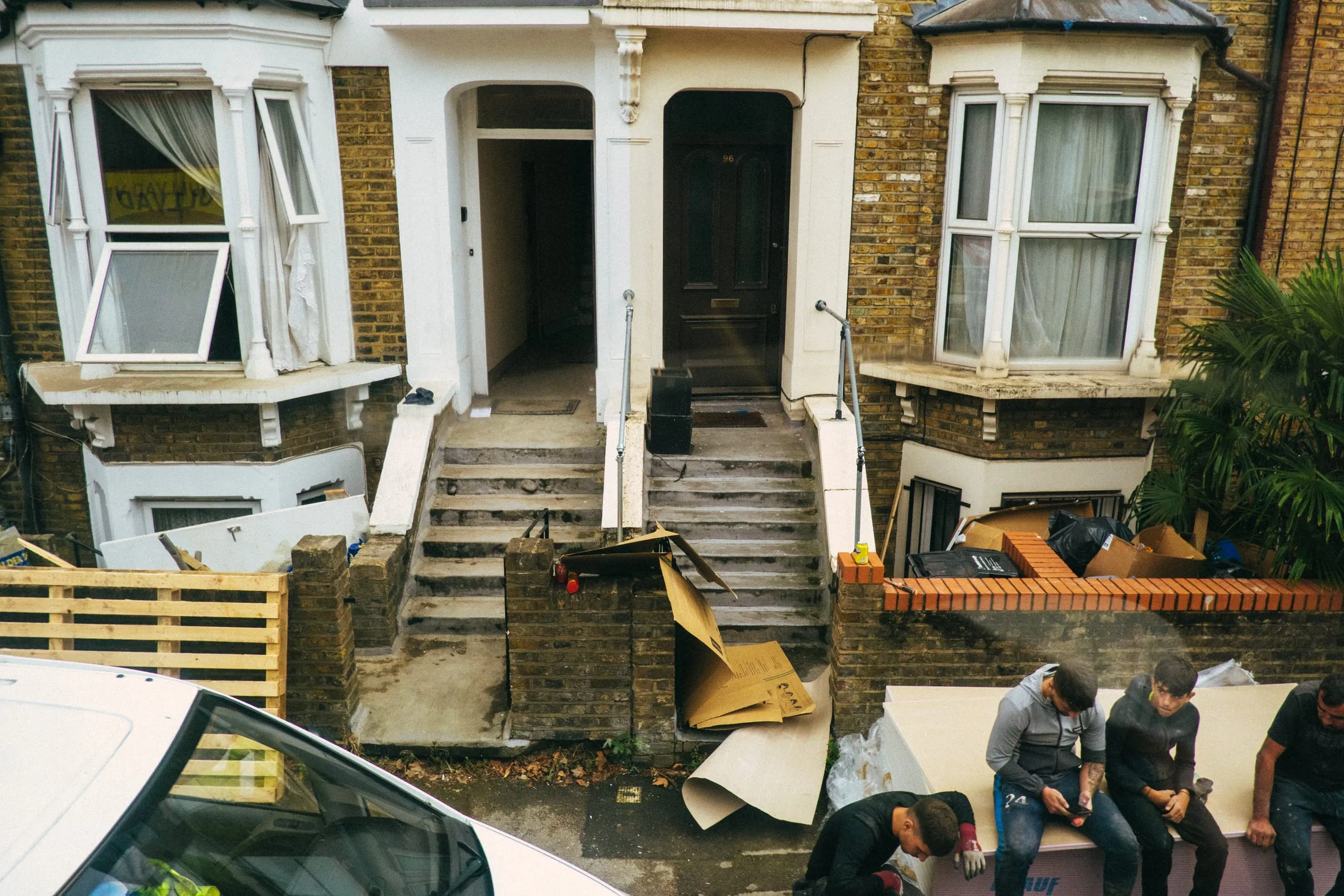 Workers sit outside a terraced house being renovated, Clapton