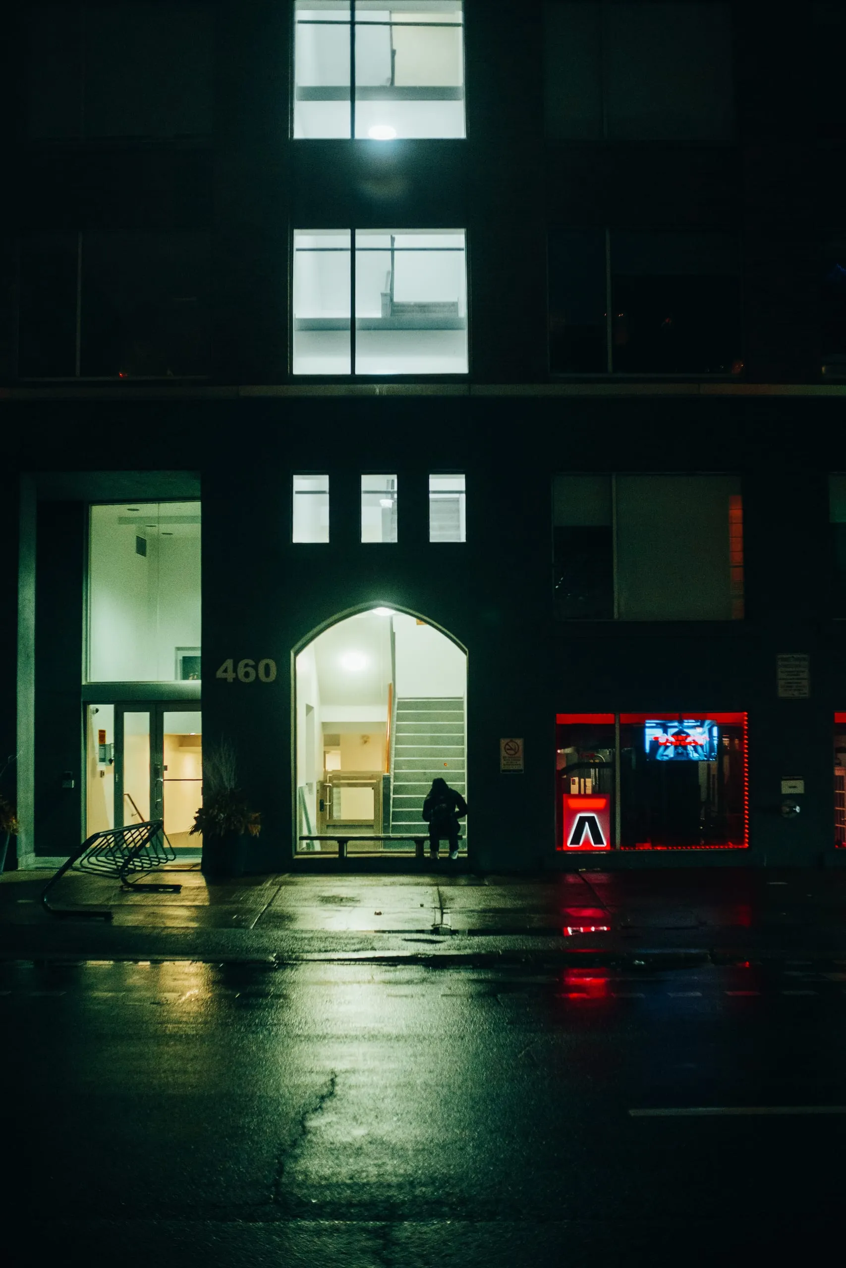 A man checks his phone at night outside an appartment block