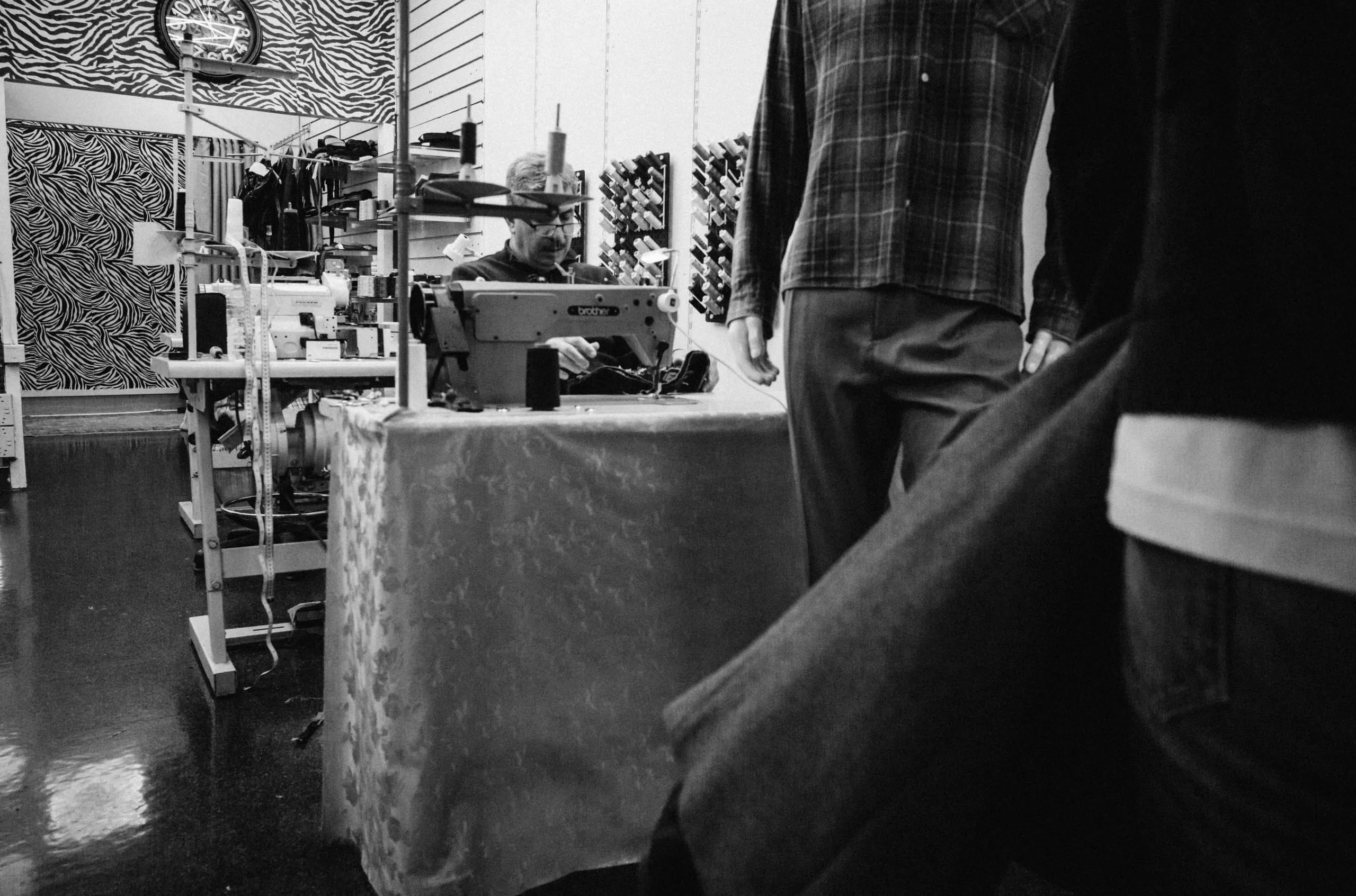 A tailor works at a sewing machine in a workshop