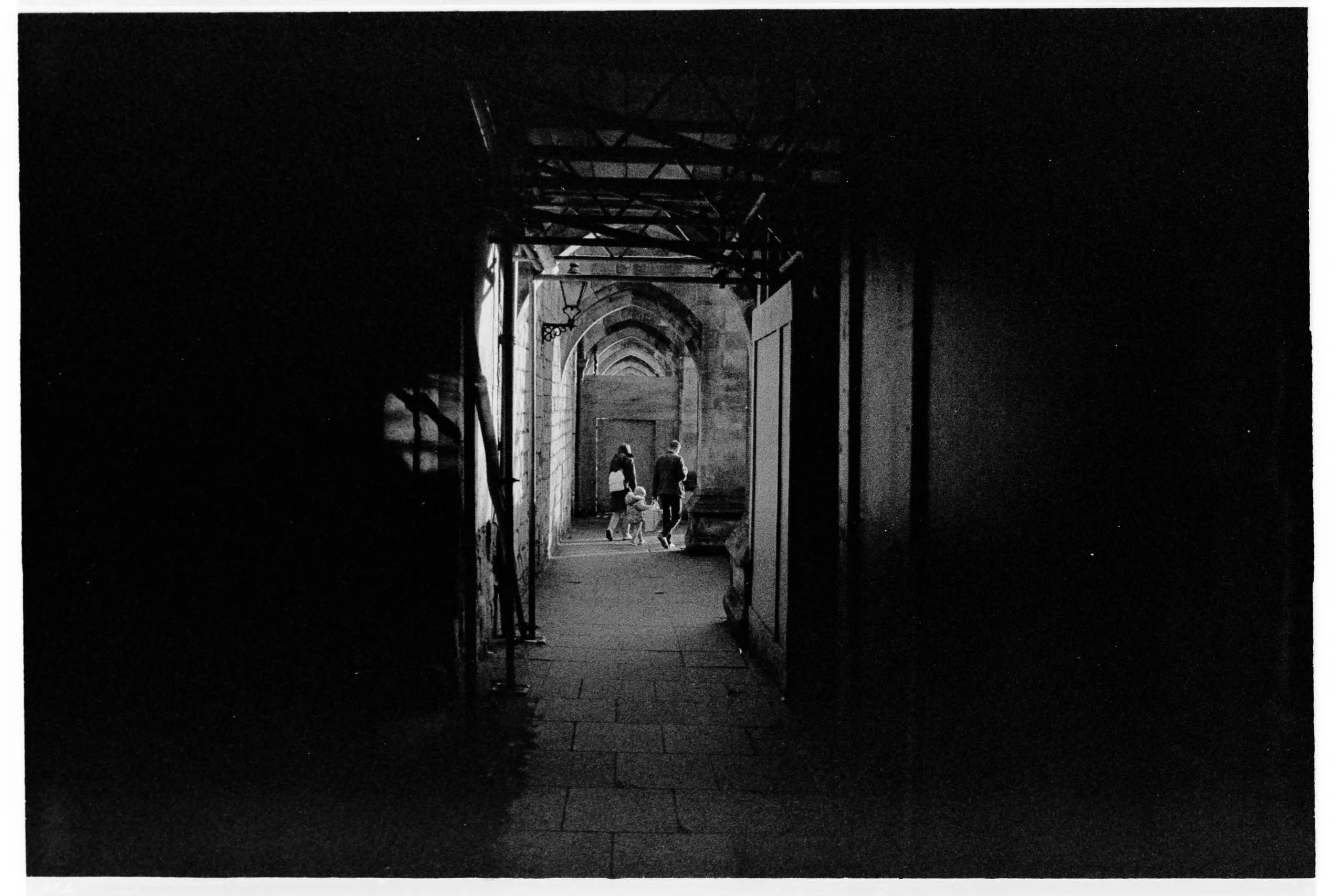 A family walks through a dark vaulted passageway