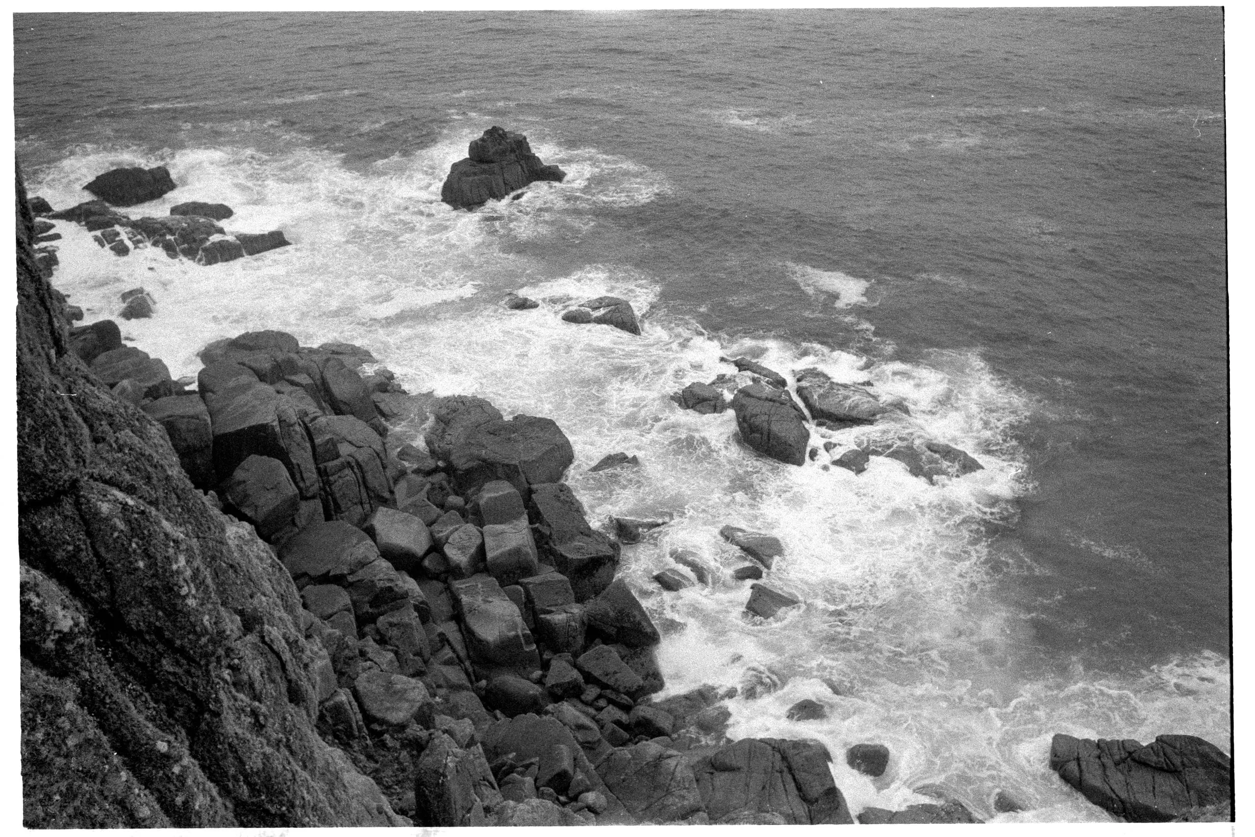 Waves hit a cliff in Porthcurno