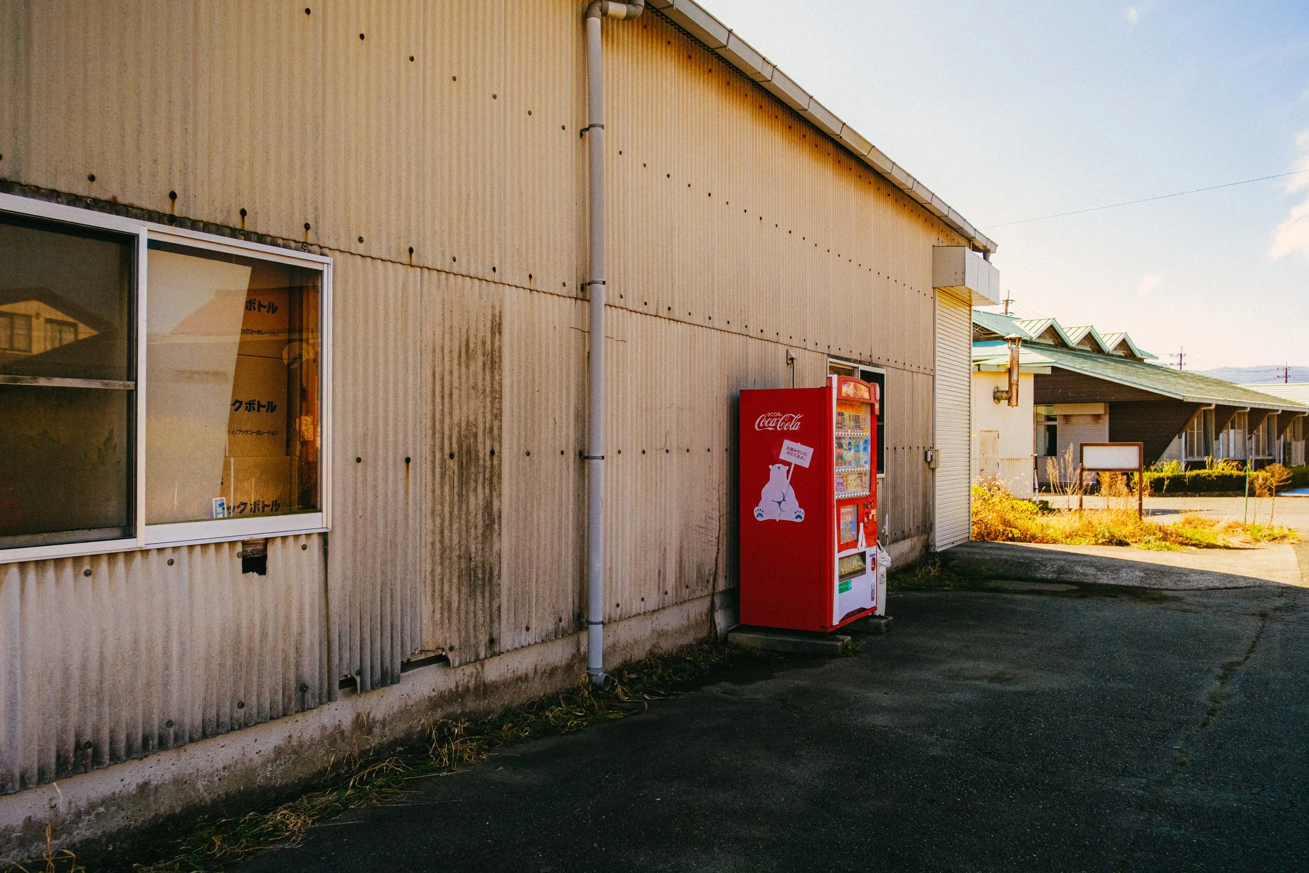 A red vending machine against a corrugated metal warehouse