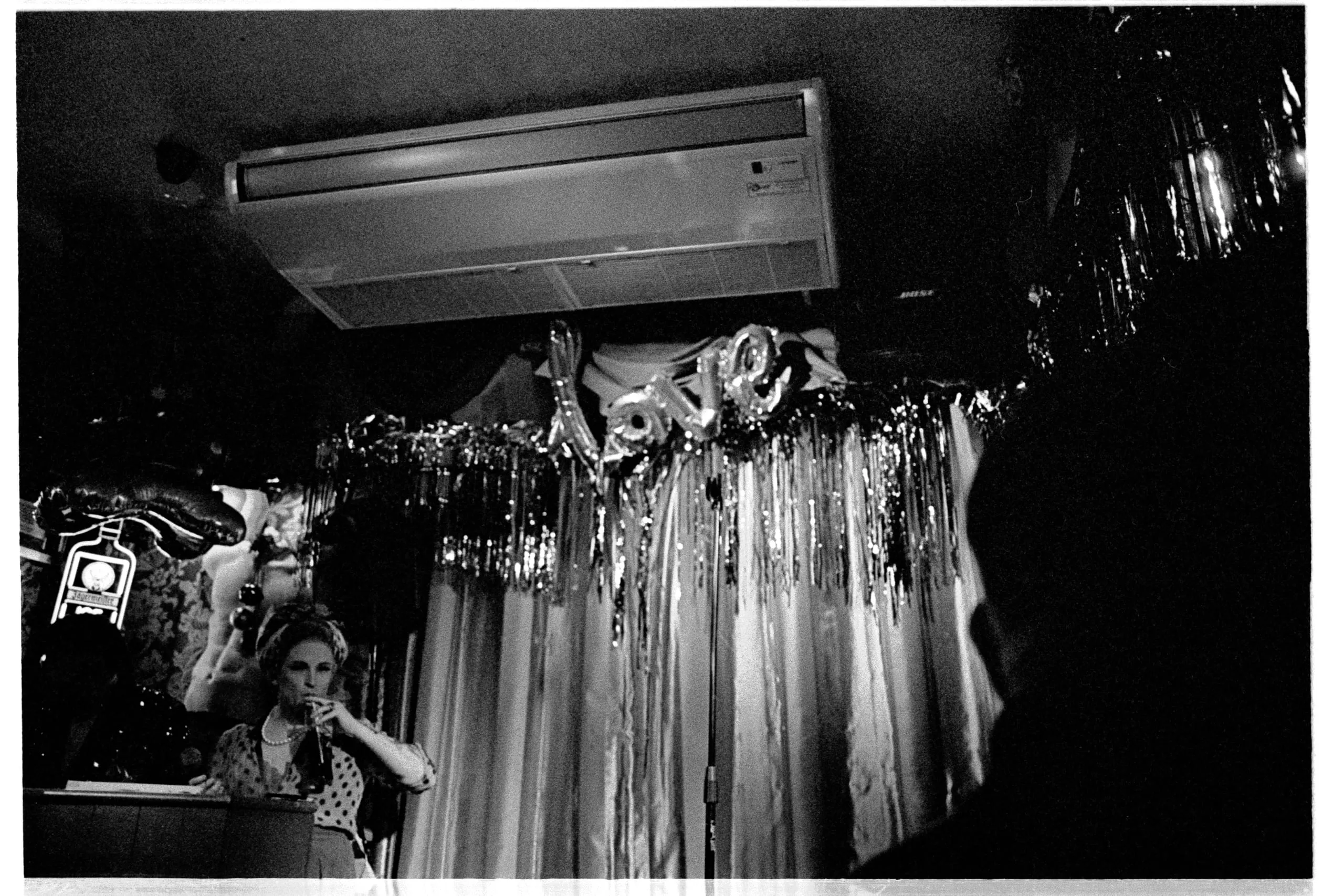 A drag performer at the Old Ship takes a sip of her drink mid-act