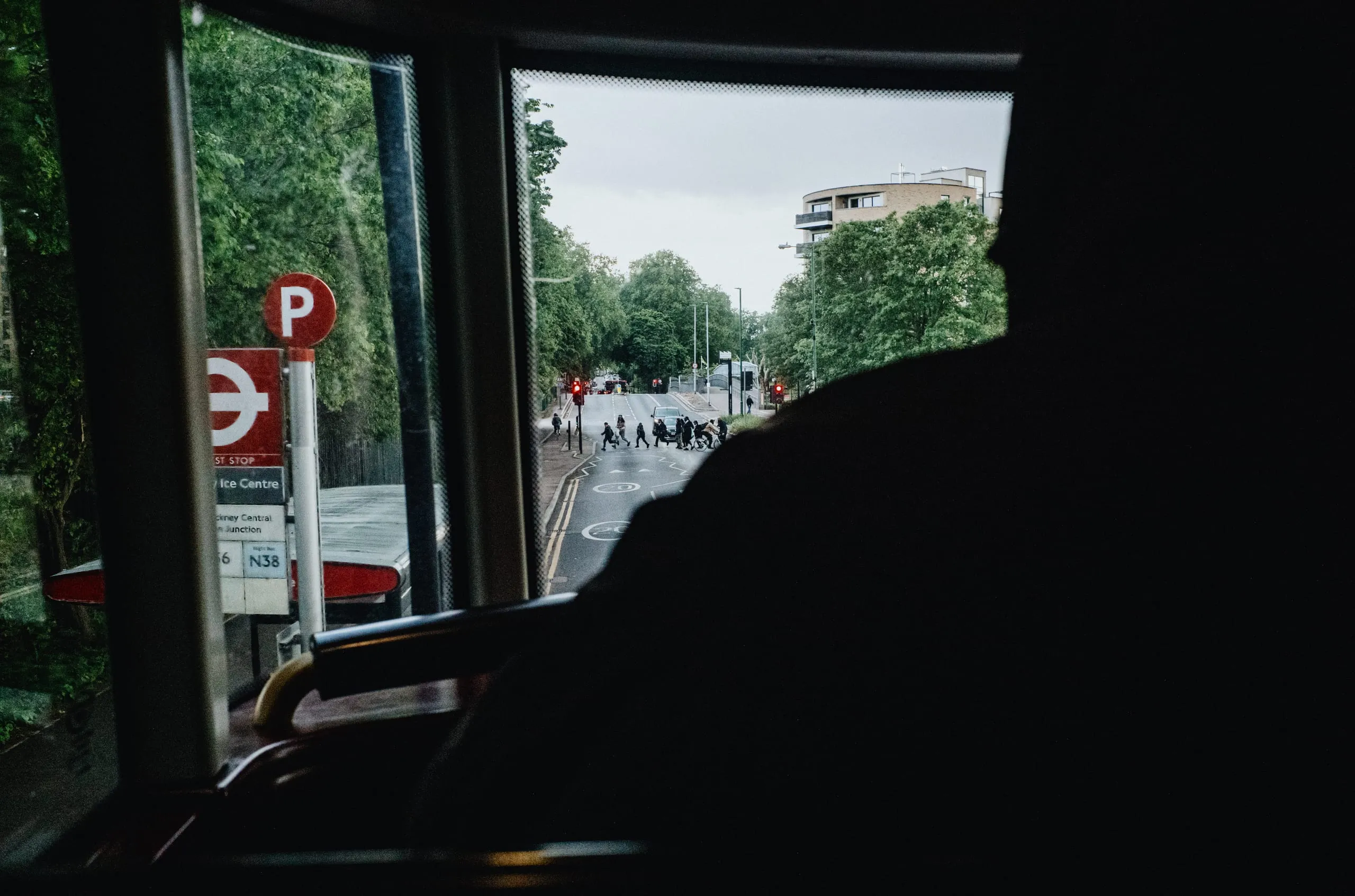 Pedestrians cross the road as seen from the upper deck of the 55 bus