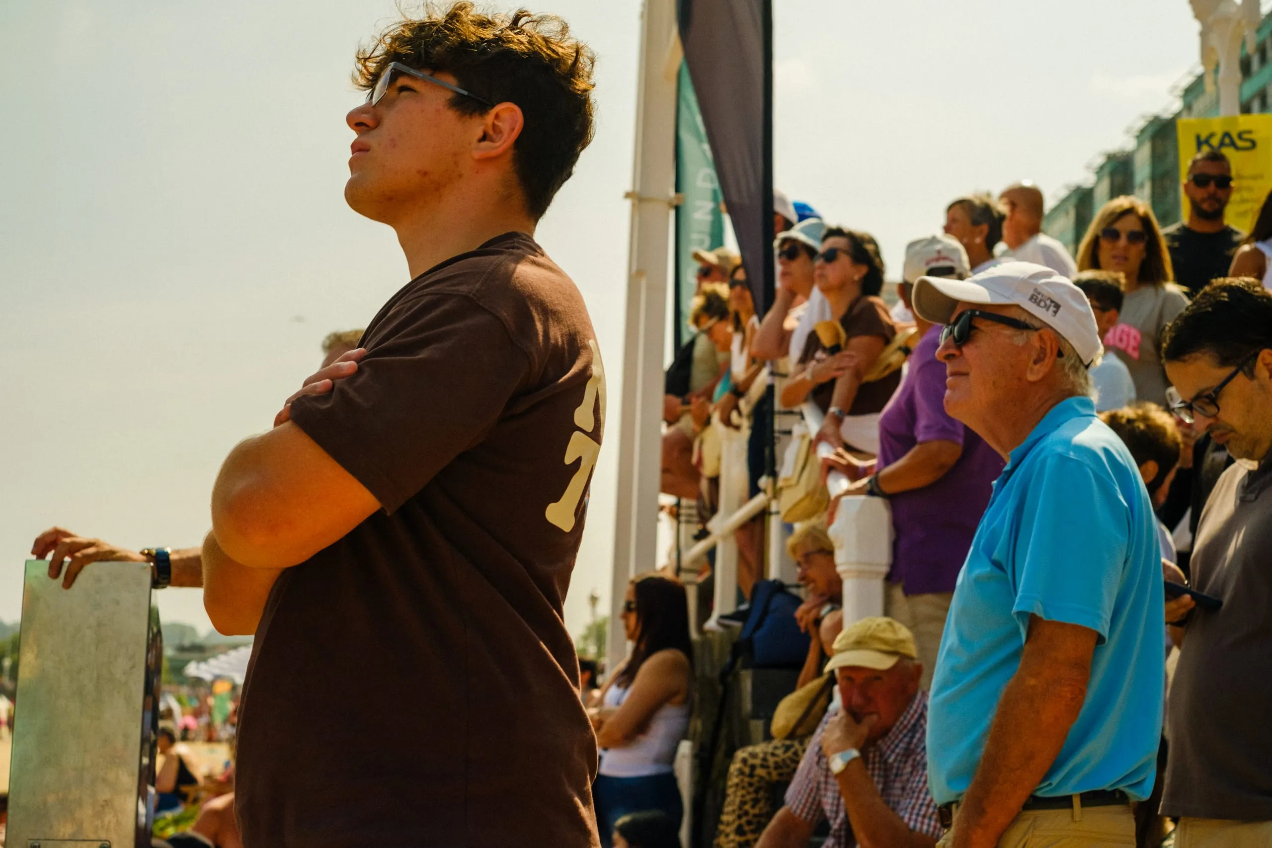 A young man watches Gijón air show from the seafront among a crowd
