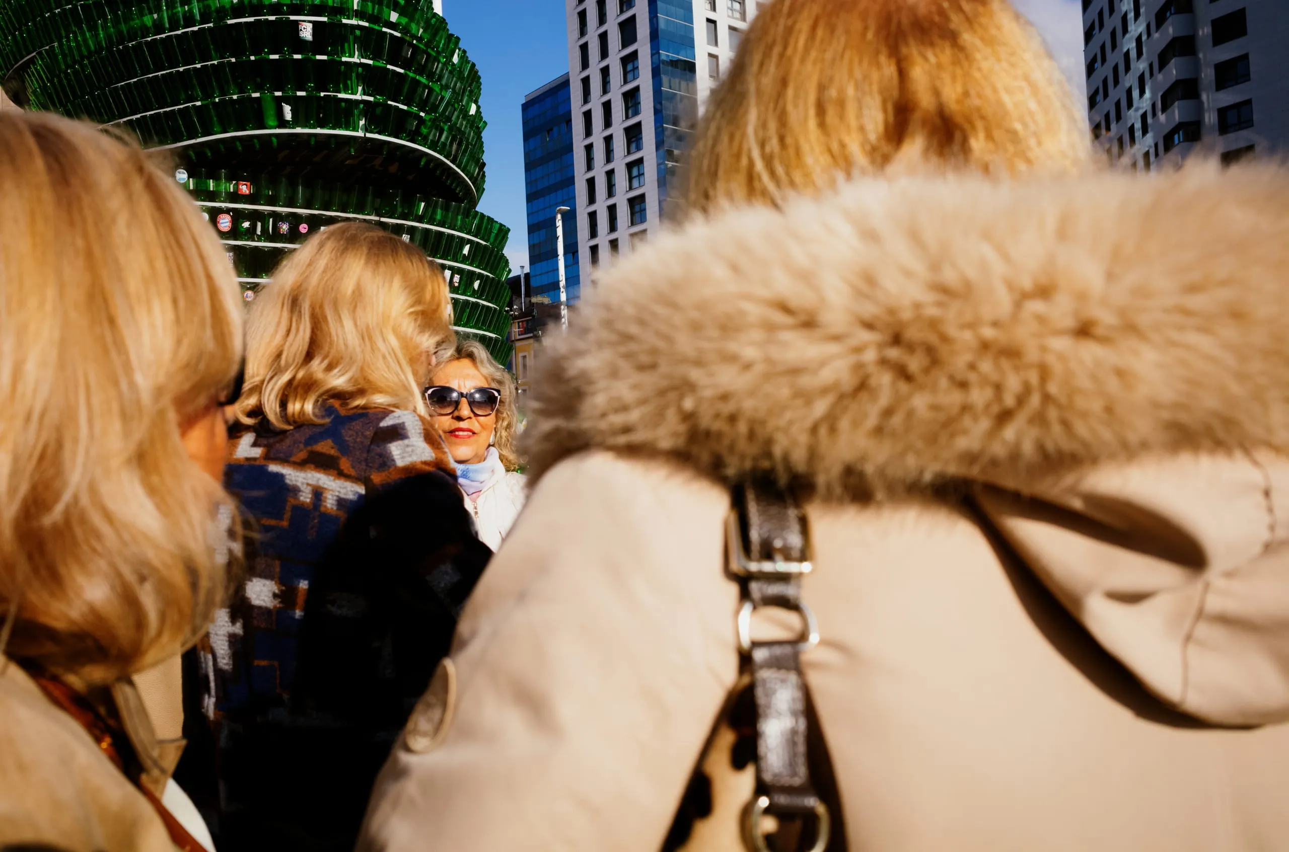 A woman in sunglasses seen between two others in fur-collared coats