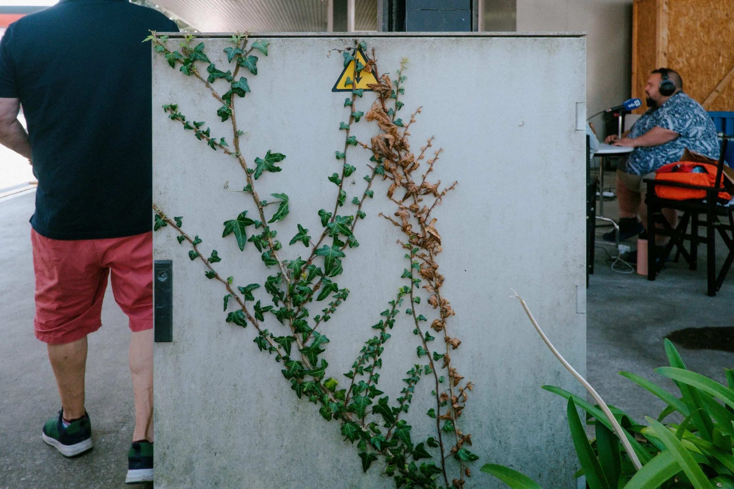 Dad passes a metal cabinet overgrown with ivy as another speaks into a microphone at Feria de Muestras de Asturias