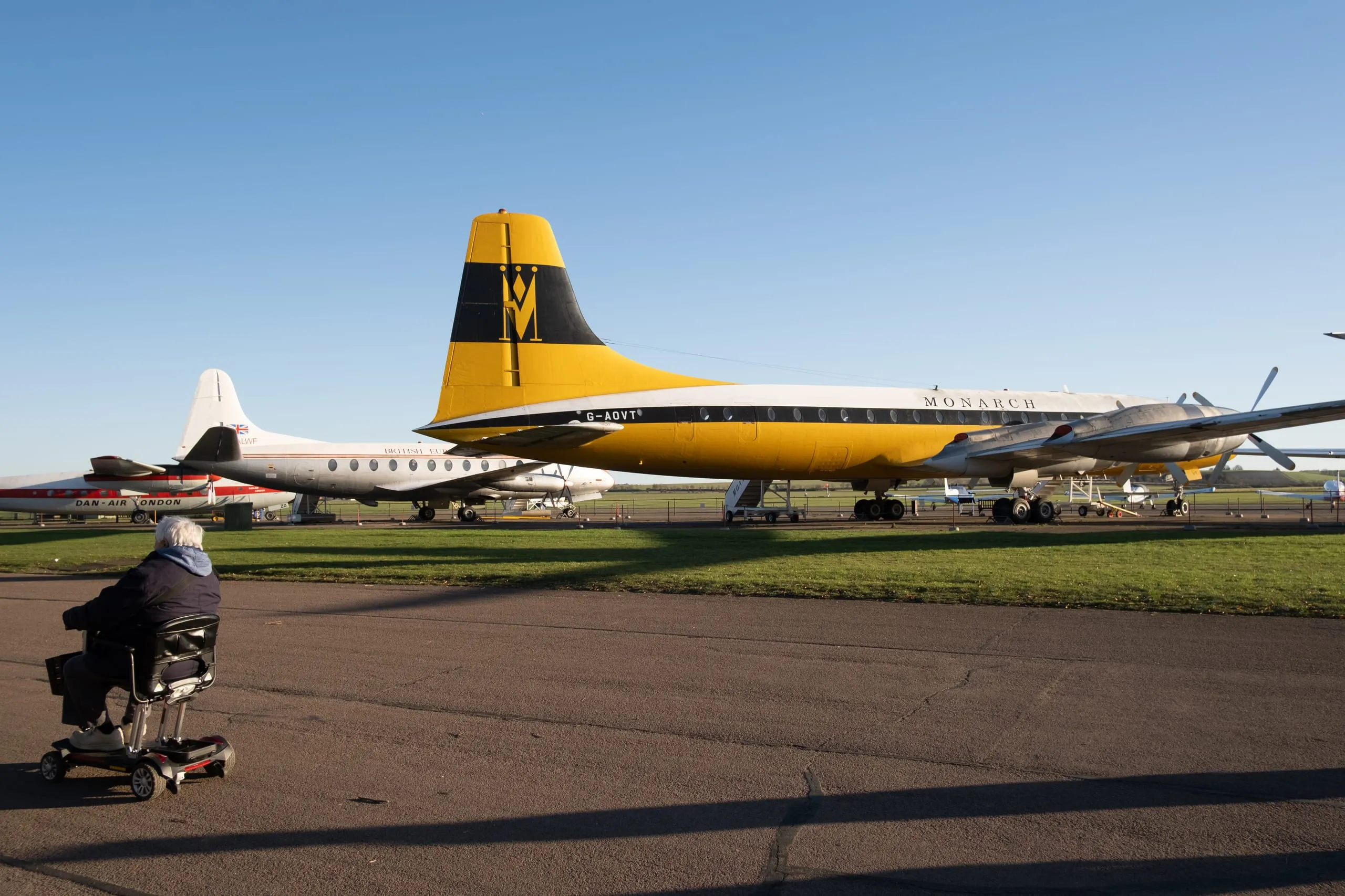 A man on a mobility scooter passes a preserved Monarch airliner