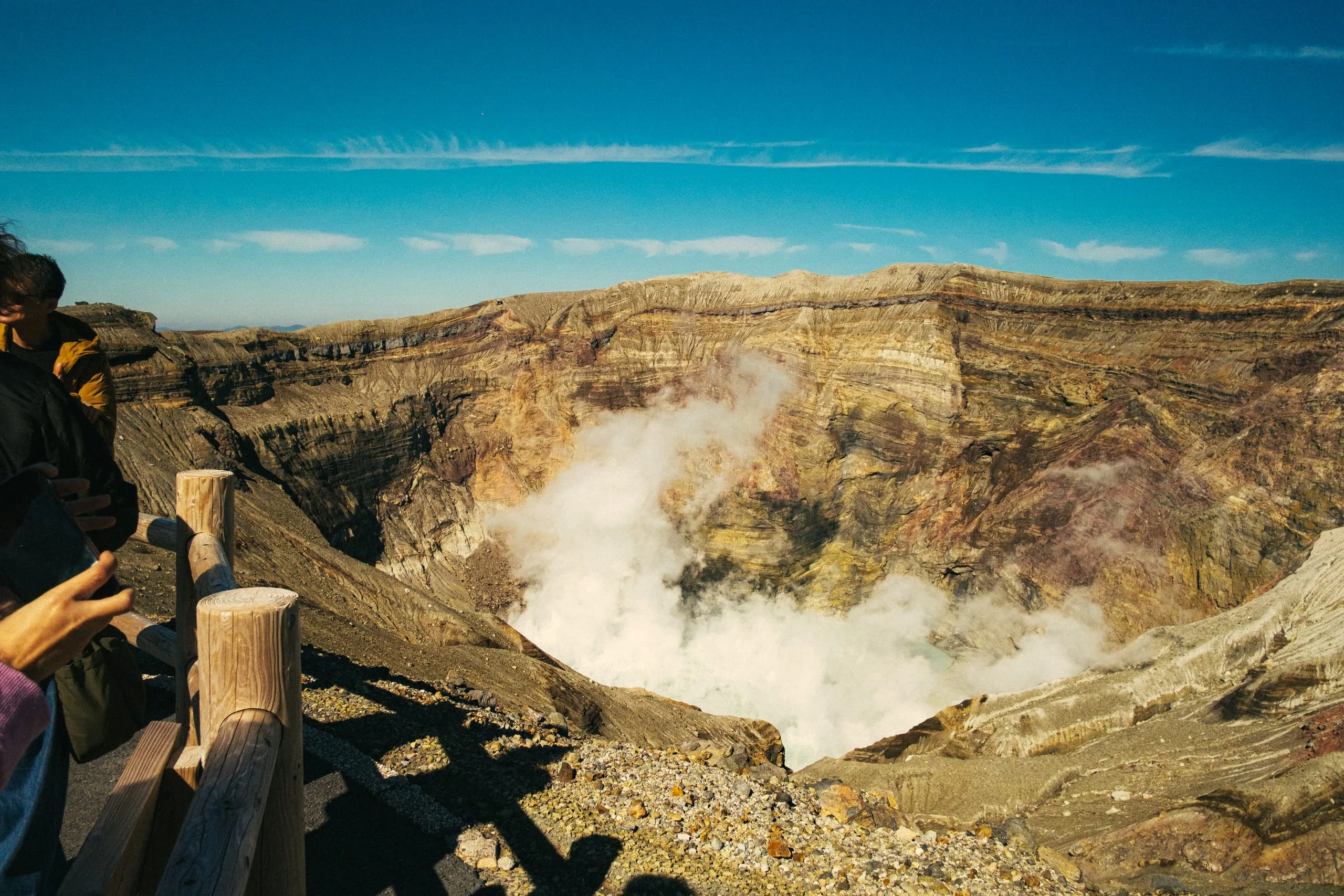 Visitors look down into a steaming volcanic crater, Mount Aso