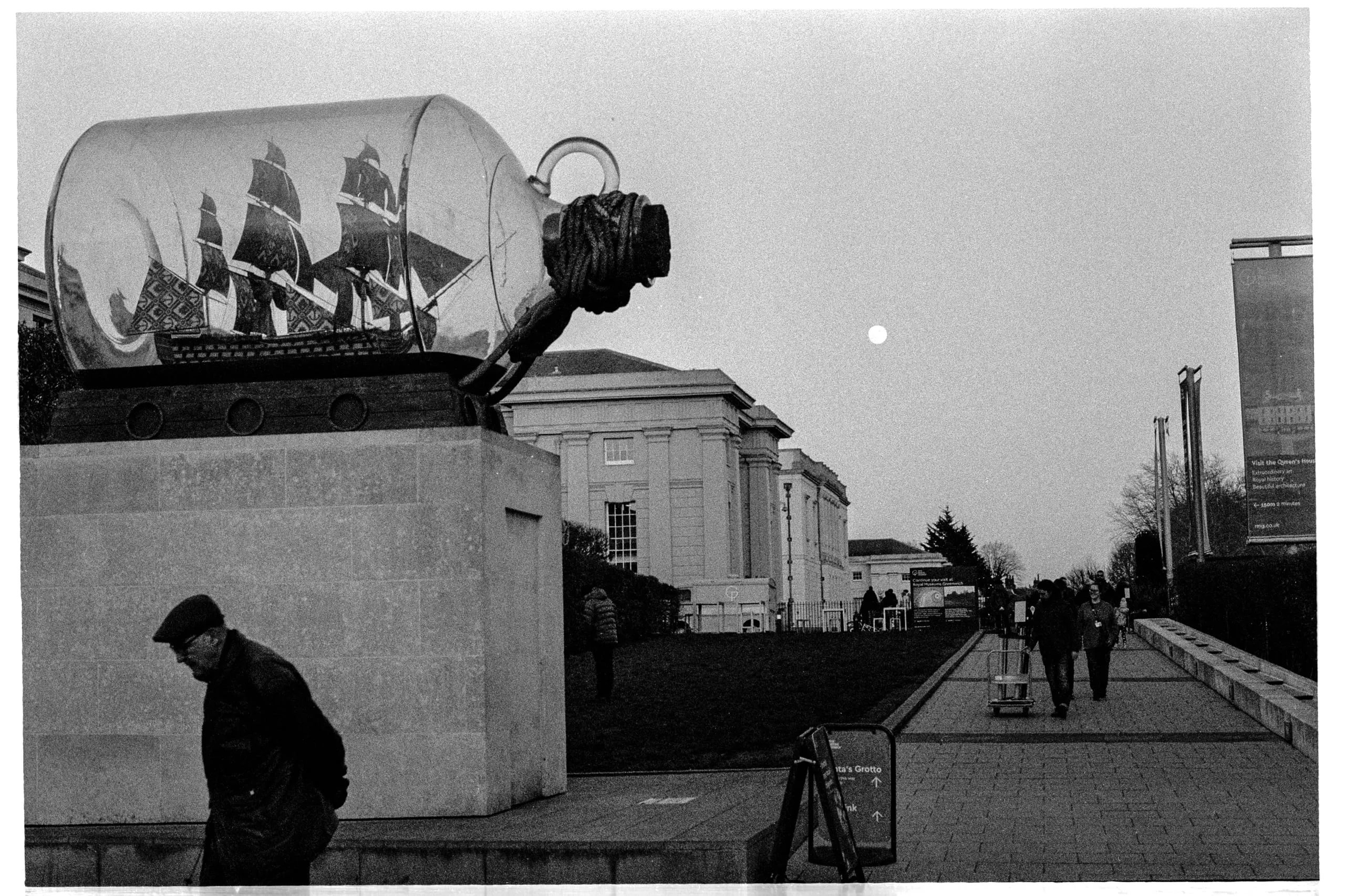 Yinka Shonibare's ship-in-a-bottle sculpture and a man walking on a full moon dusk, Greenwich