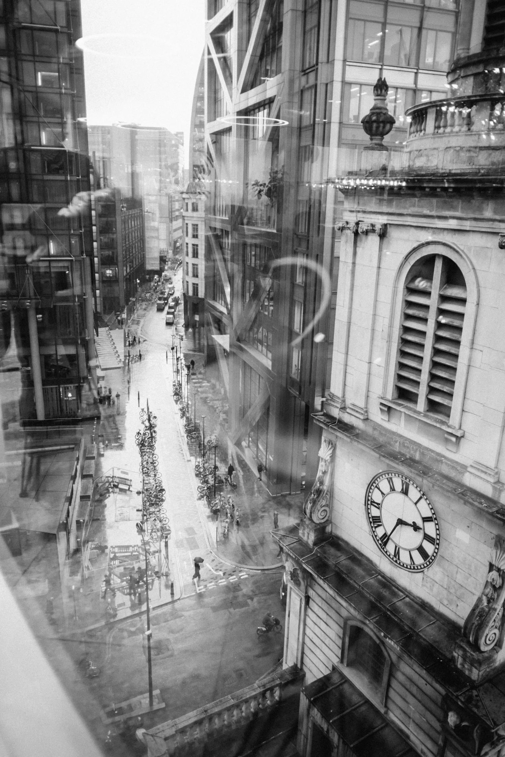 A City street and a clock seen through a reflective window, London