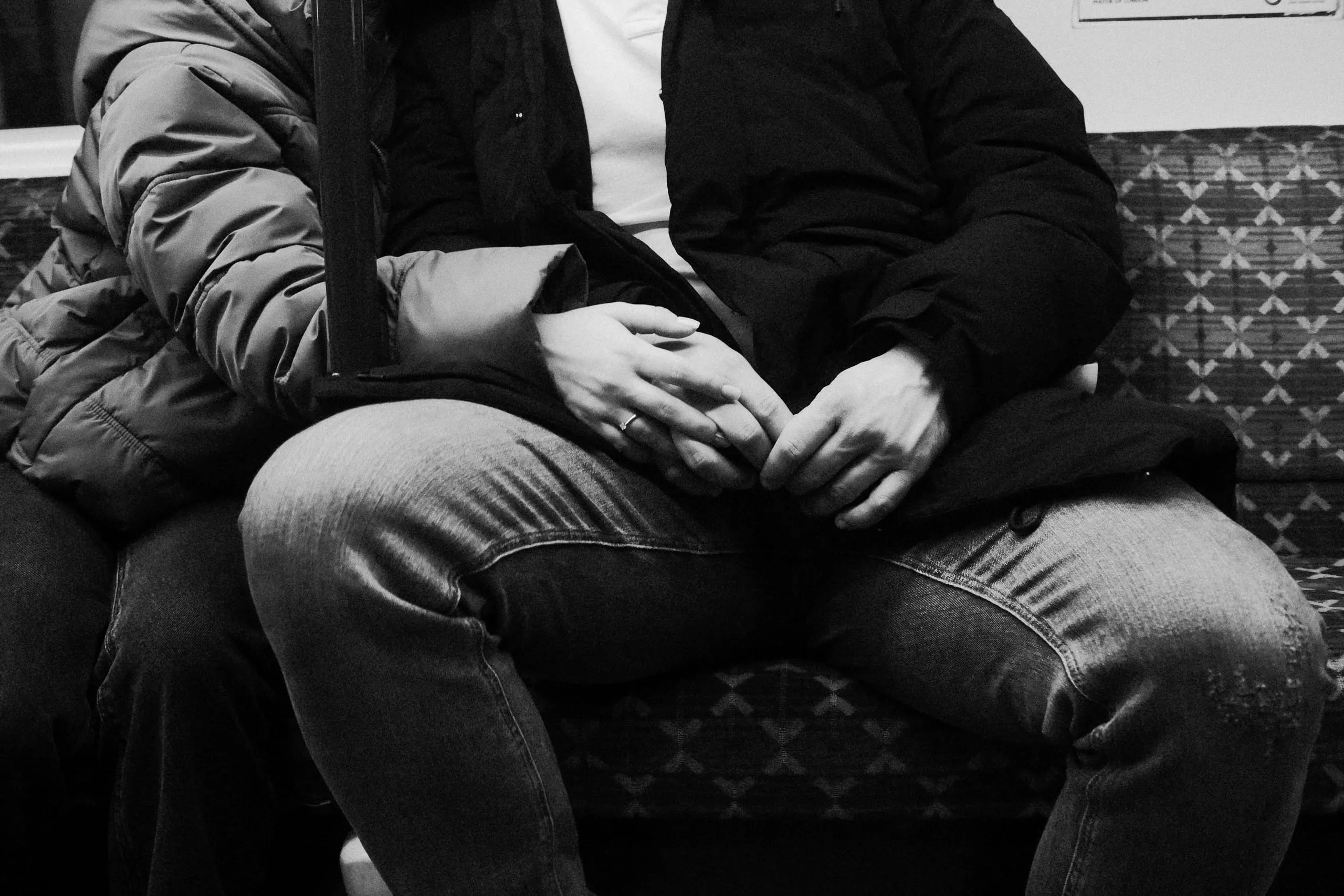 A heterosexual couple hold hands in a tube carriage, London