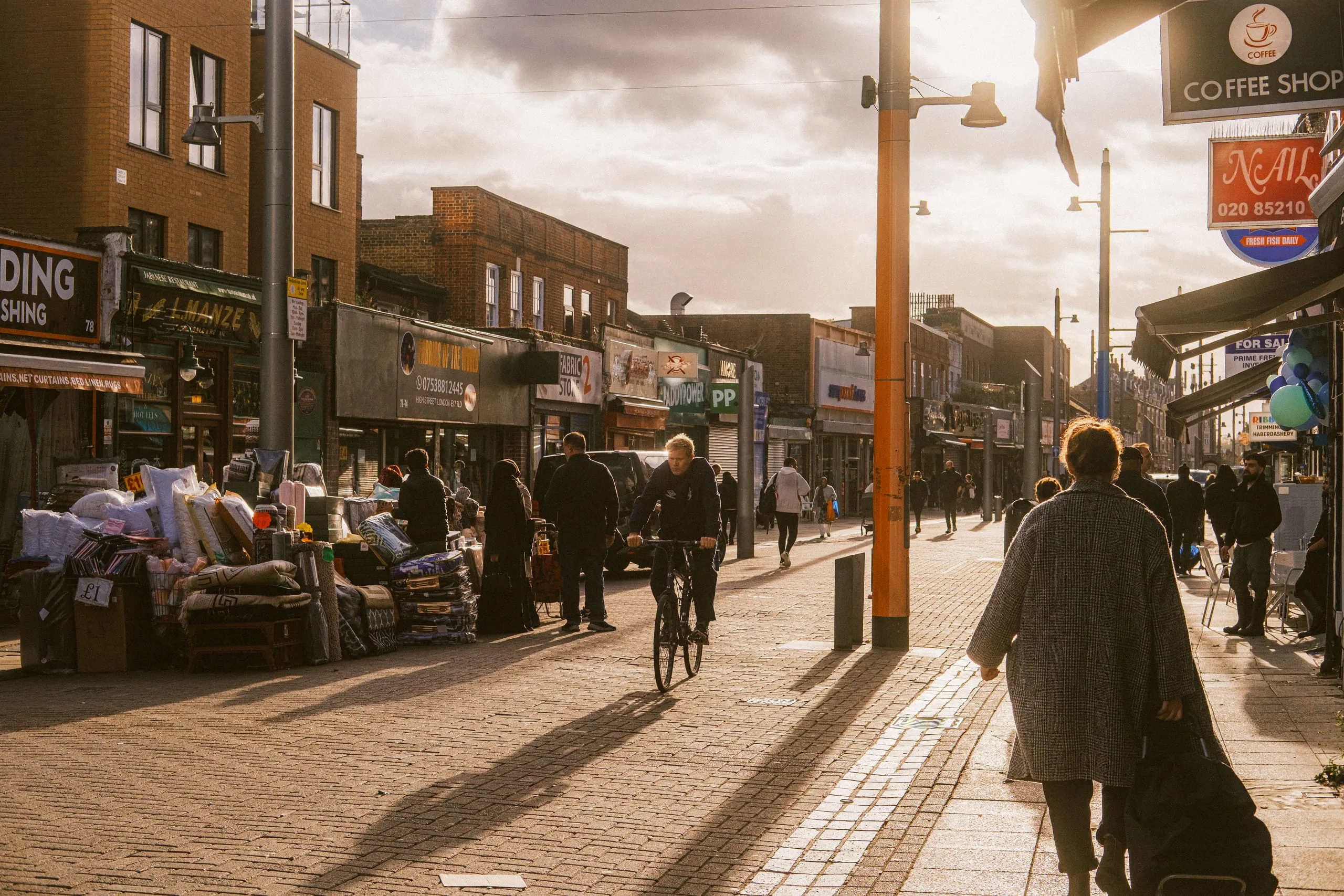 A cyclist rides through Walthamstow High street market in the late afternoon sun
