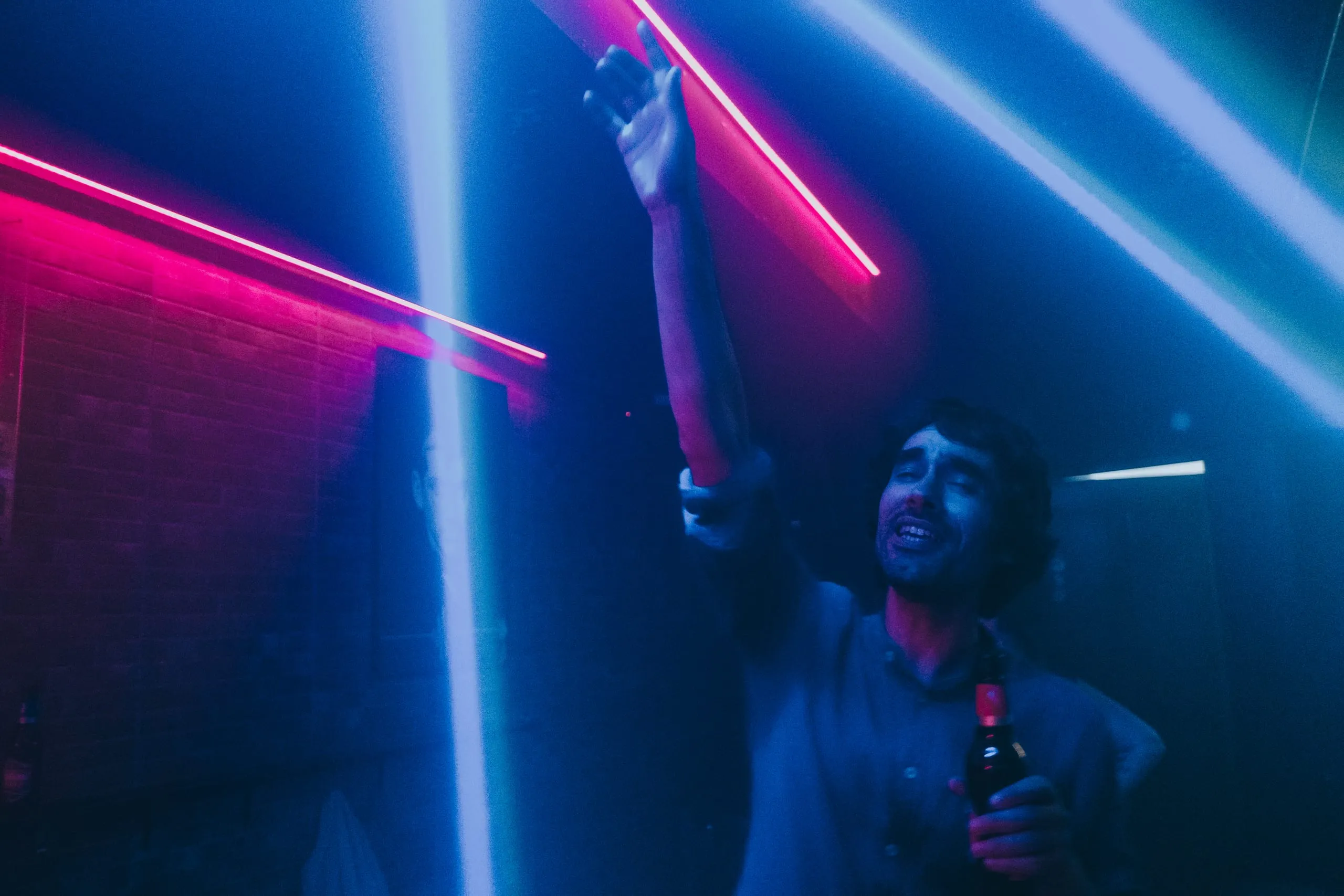 Santos dances with a beer under neon lights at a club