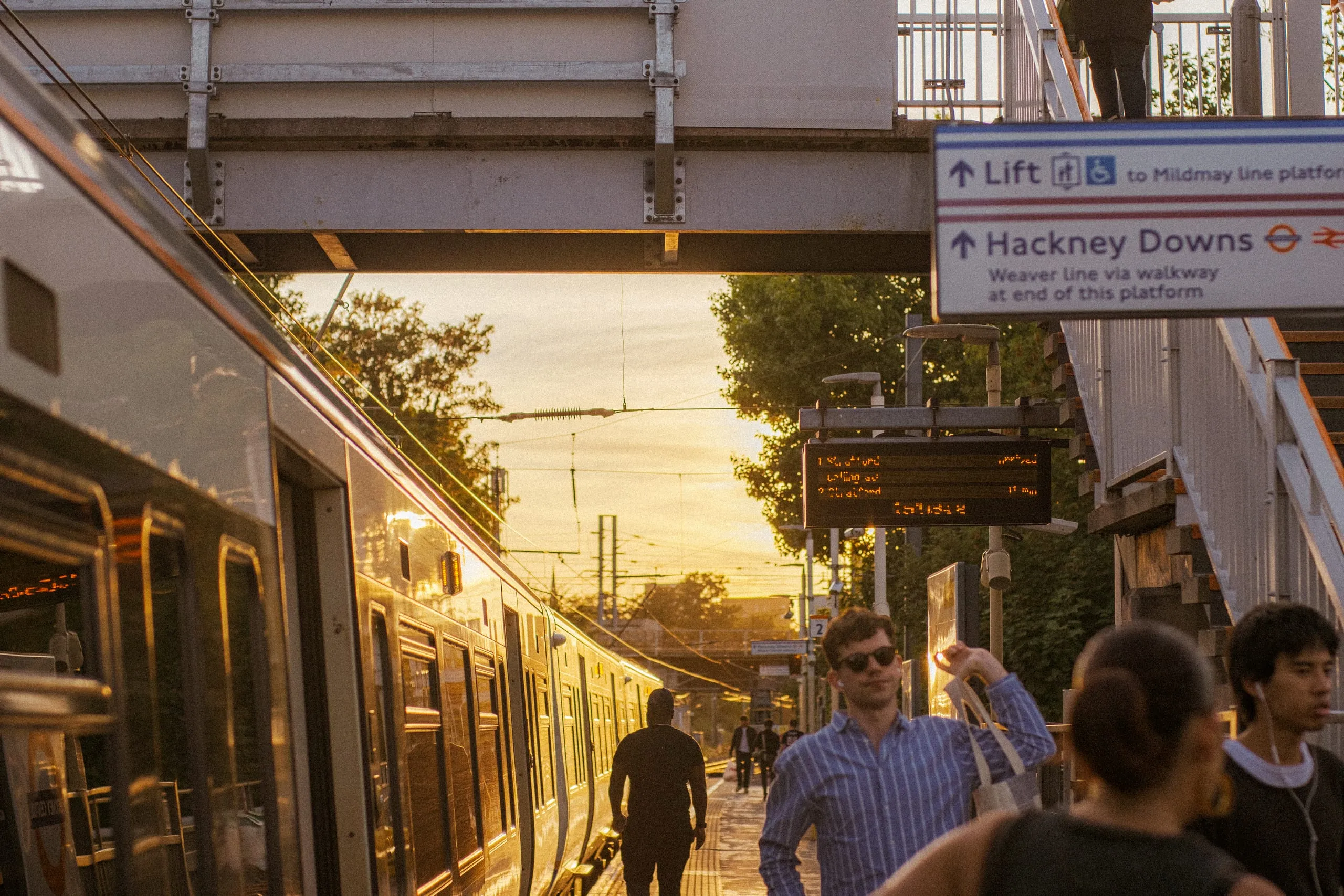 Commuters wait on the platform at sunset, Hackney Downs station