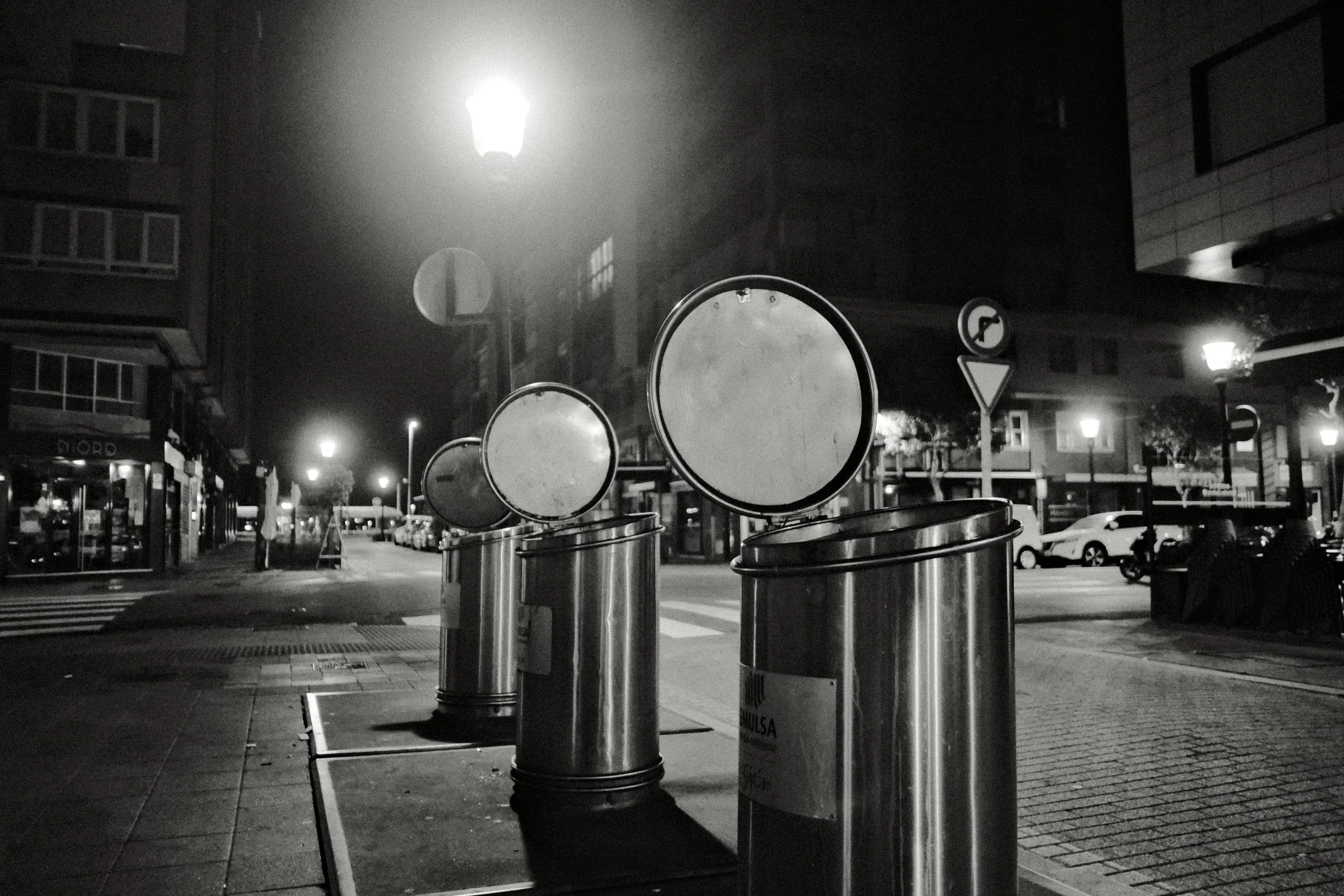 Steel litter bins on a street corner at night