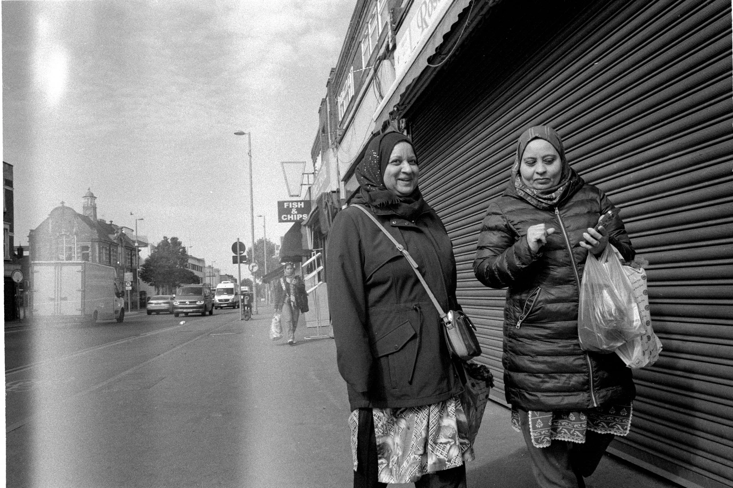 Two women converse as they walk down Lea Bridge Road