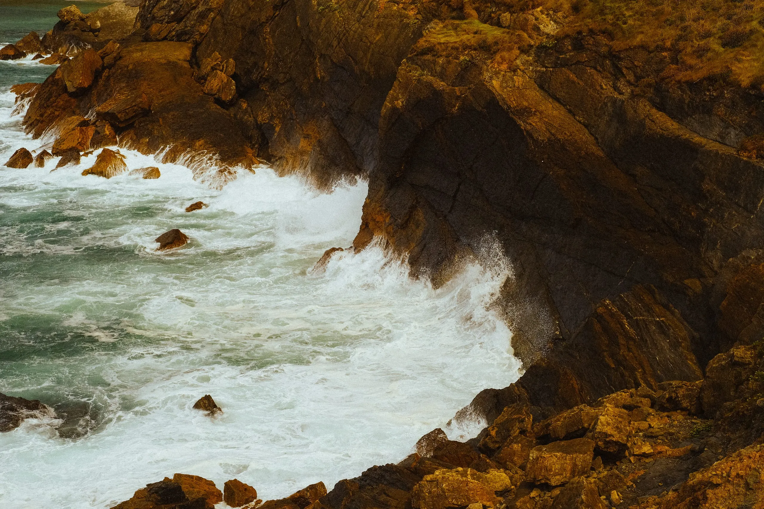 Waves break against the base of a rocky cliff, Verdicio