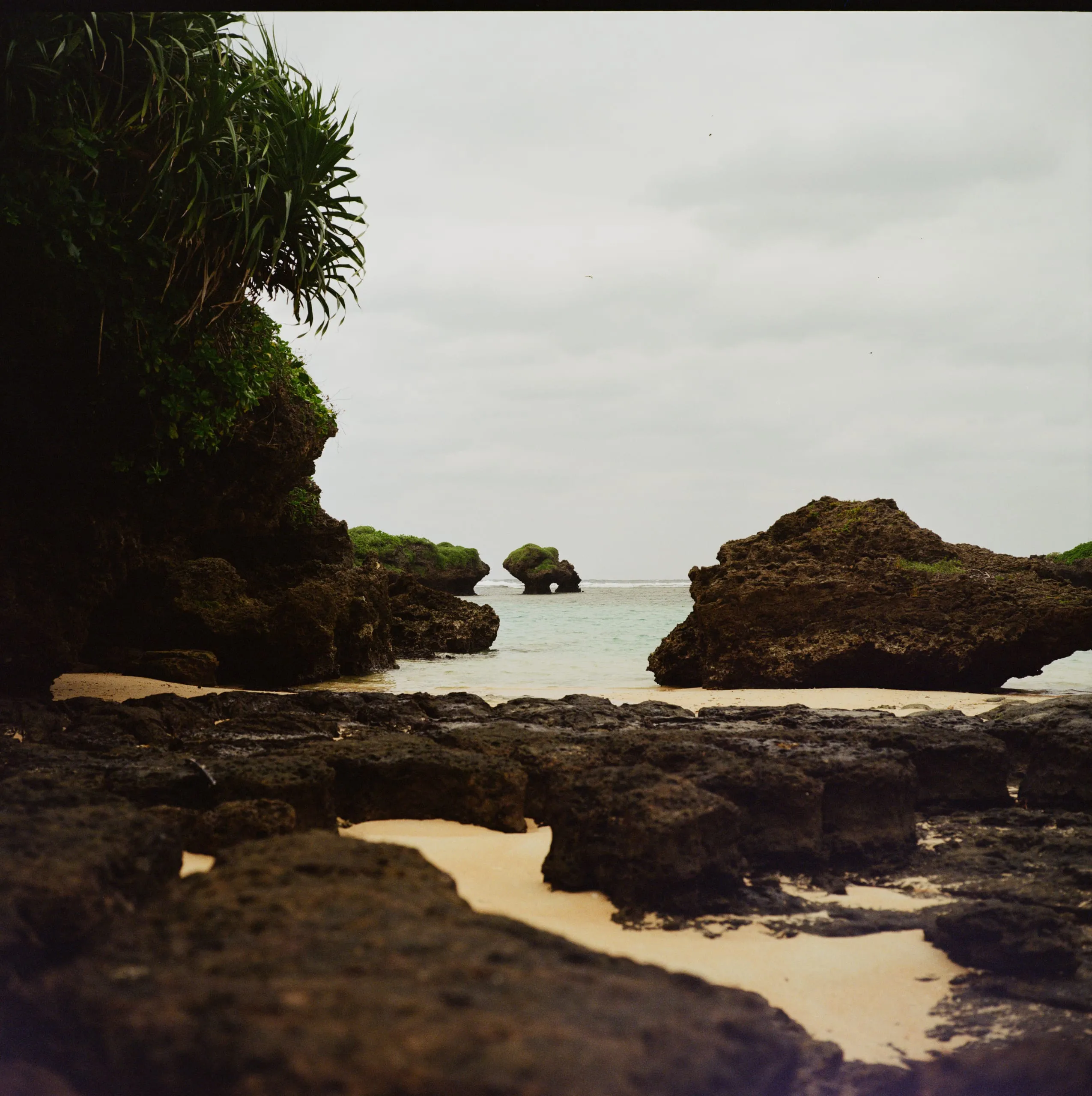 Rocky outcrops and a shallow cove under an overcast sky