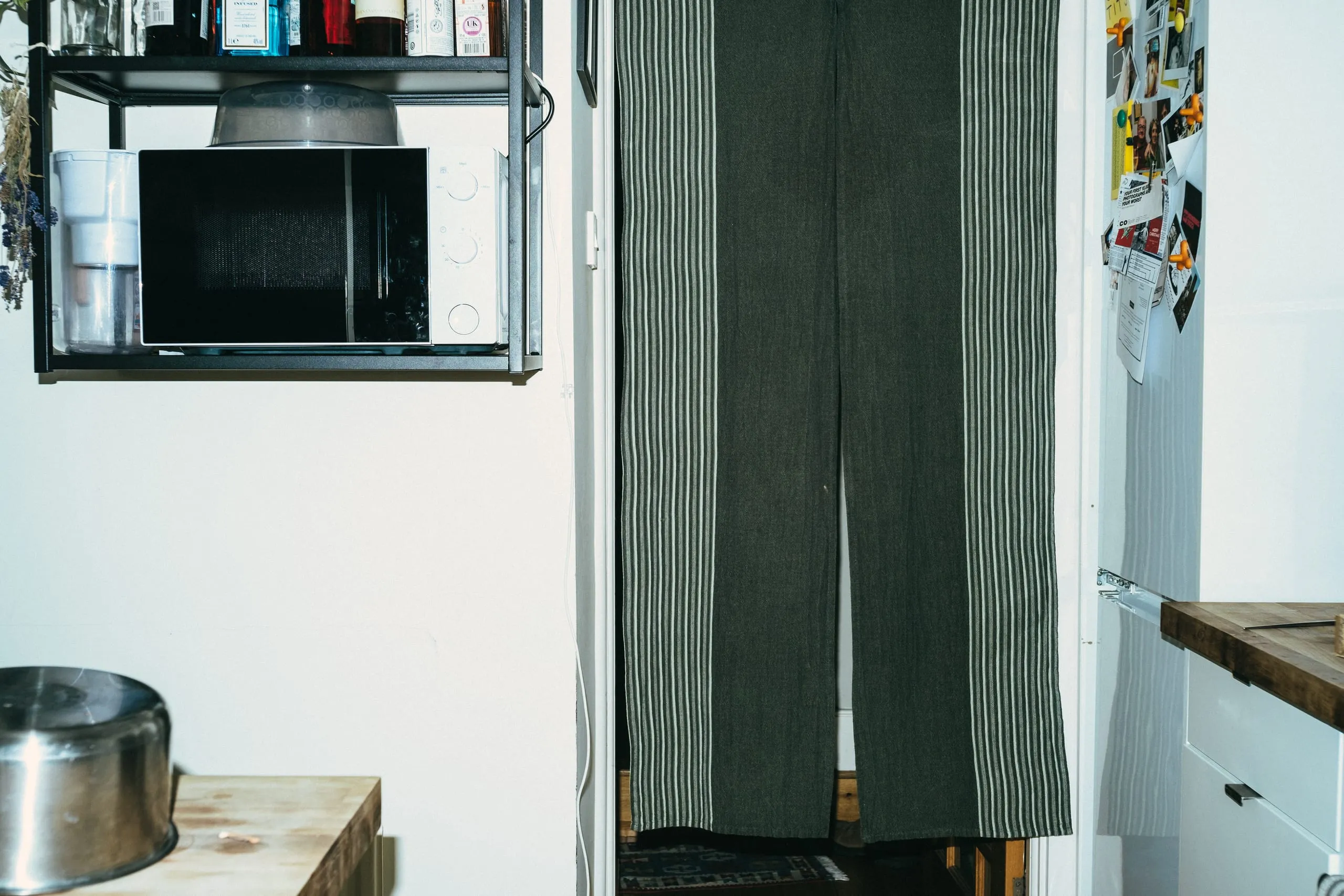 A curtained doorway beside a wall-mounted microwave in a kitchen