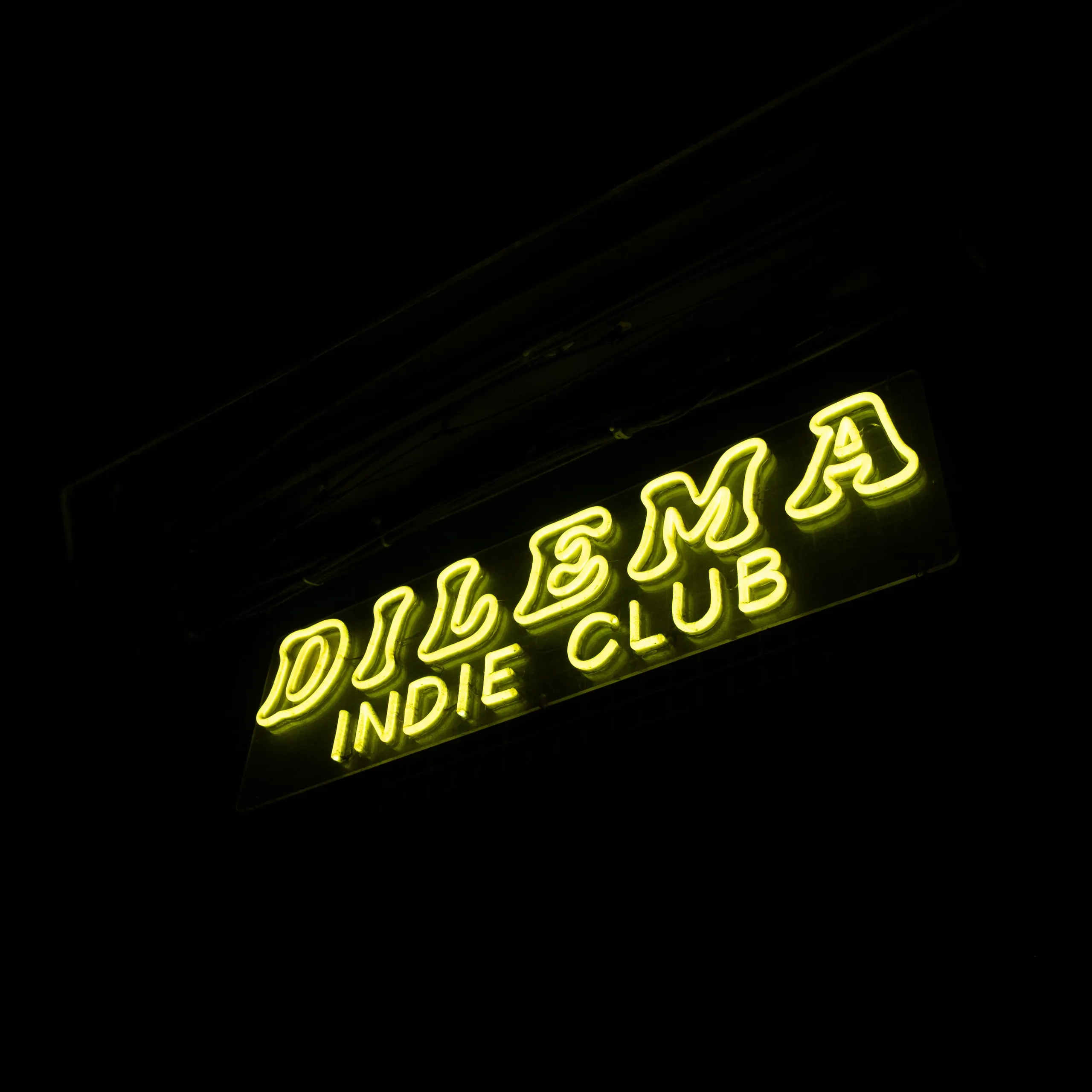 The neon sign of the Dilema indie club lit up at night