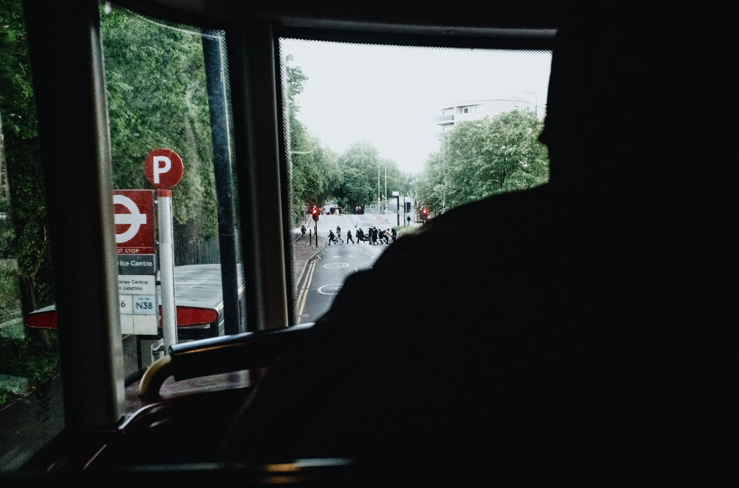 A man looks over from a double-decker bus to a group of children crossing the road