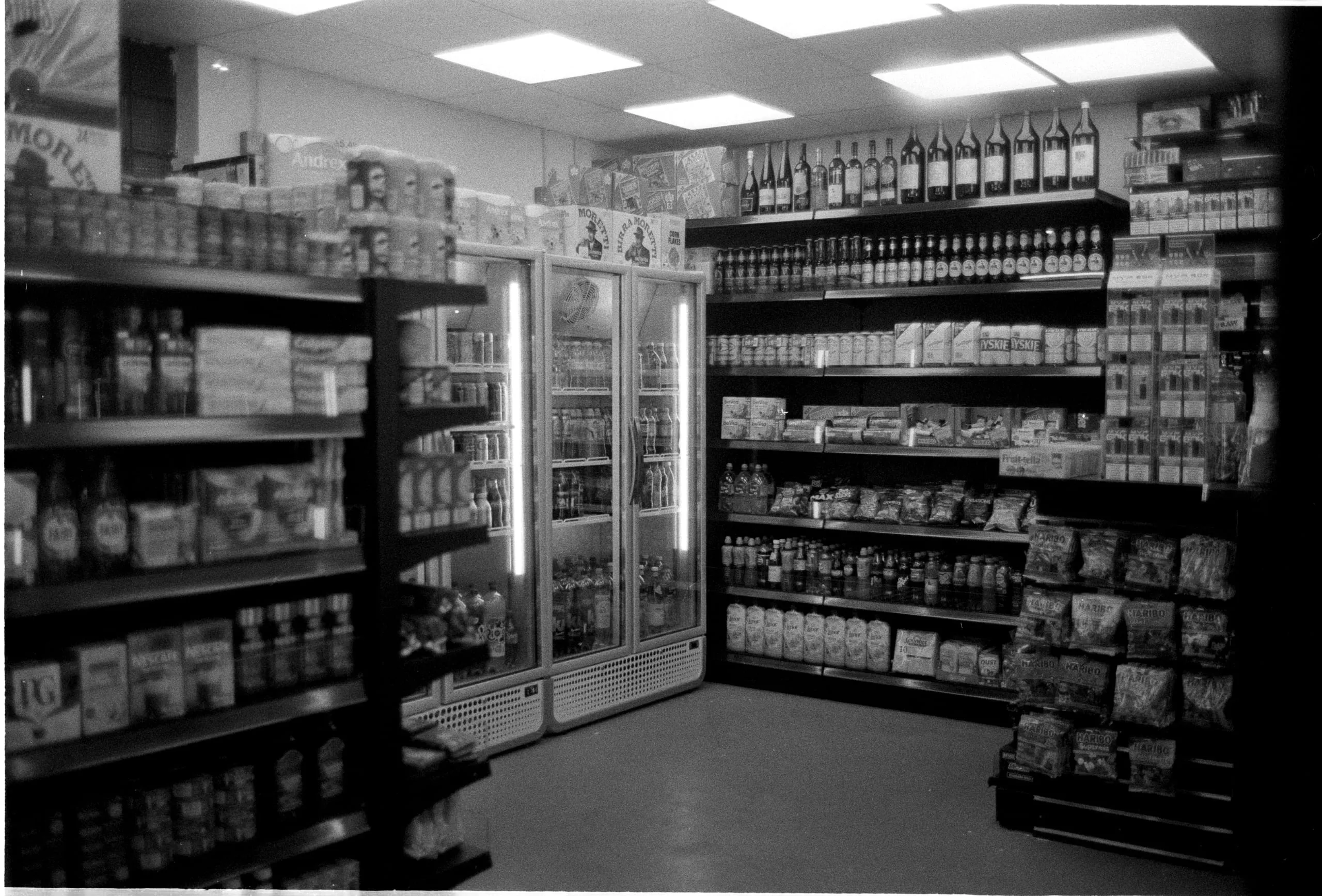 Shelves stocked with tinned goods, drinks and wine in a corner shop