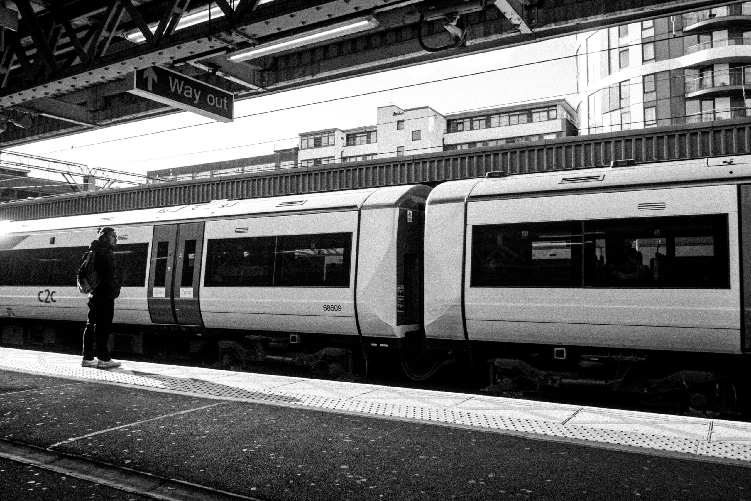 A man waits on the platform beside a c2c train