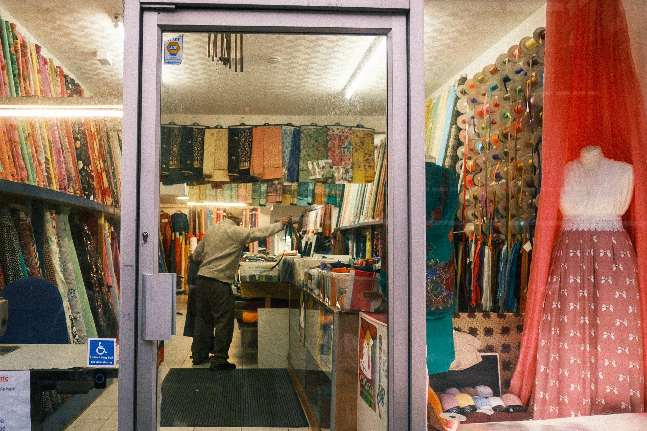 A tailor organises zippers in a fabrics shop, Leyton