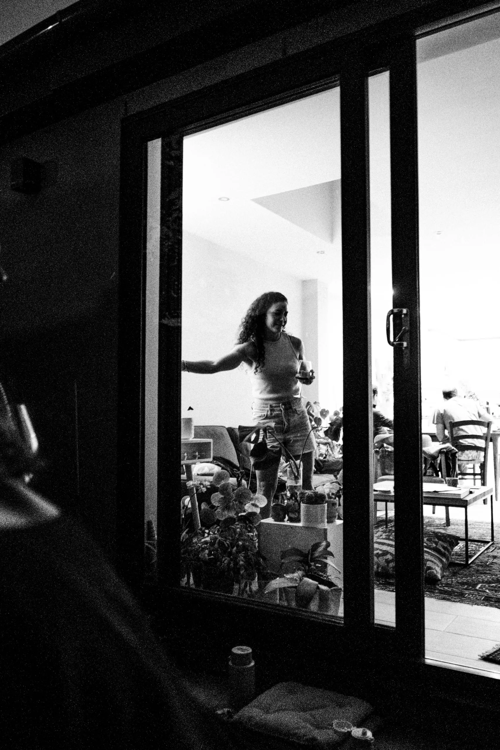 A woman seen through a glass door at an evening gathering