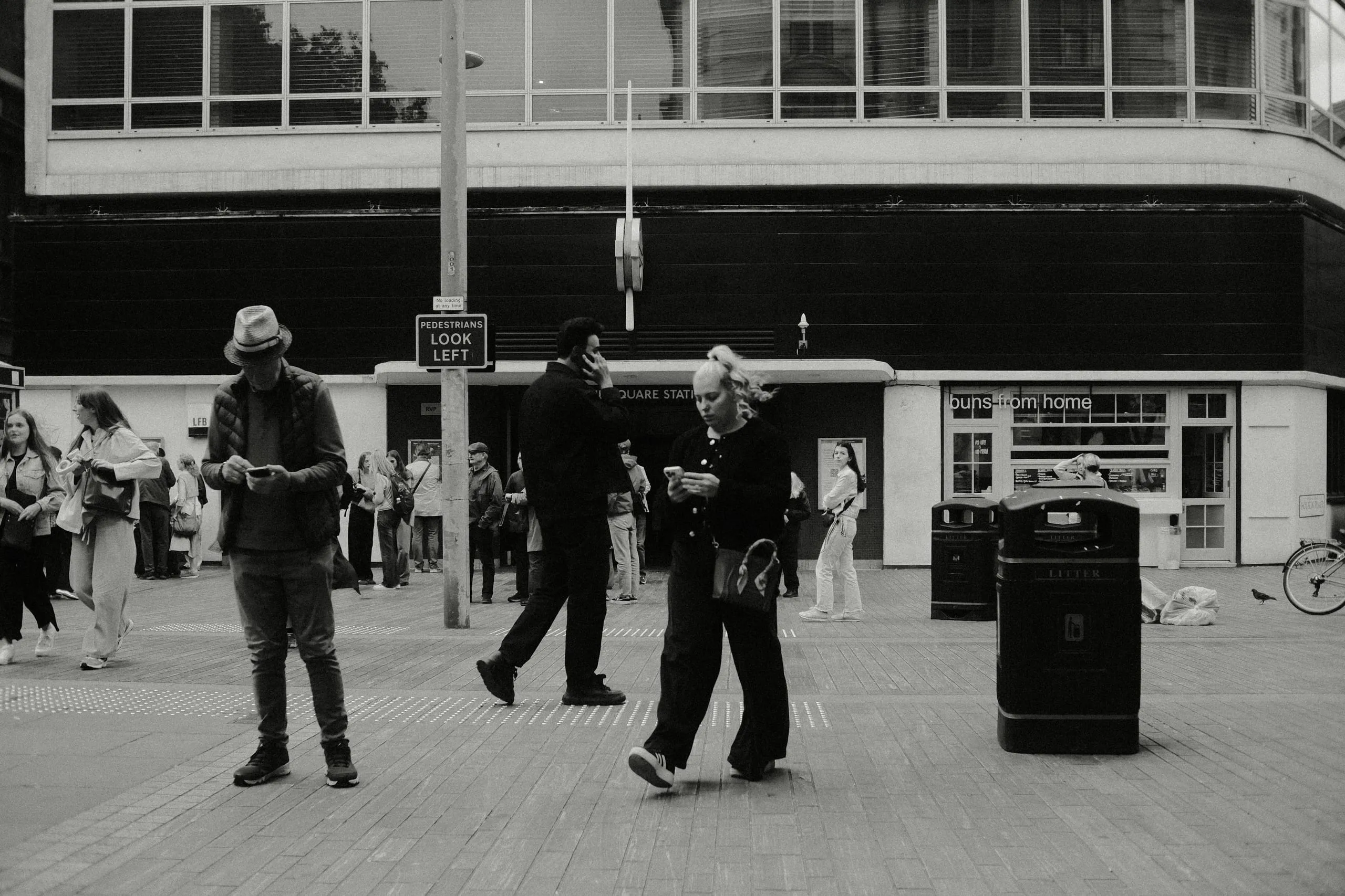 People look at their phones while walking by Sloane Square