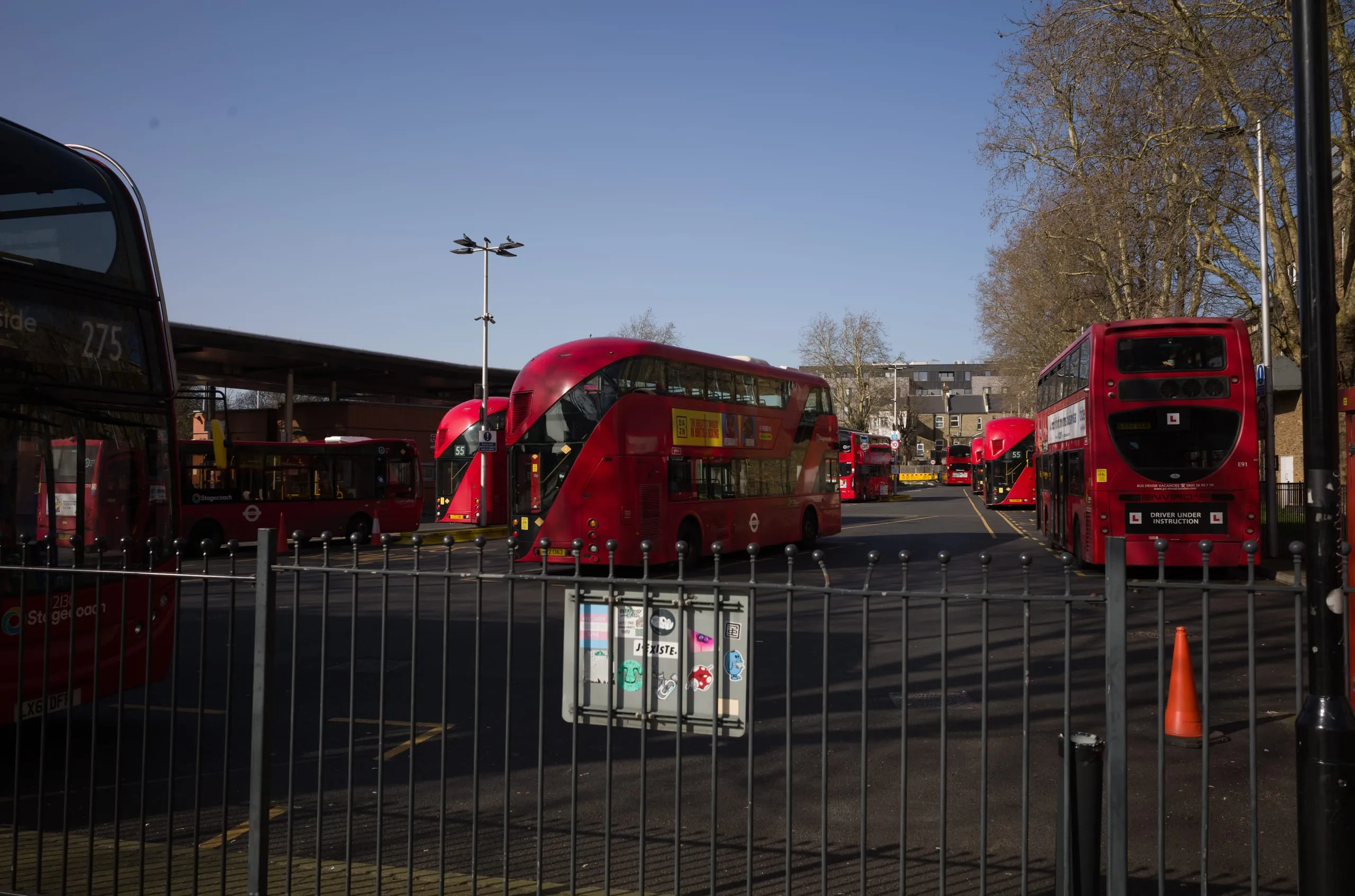 Red double-decker buses lined up at Walthamstow bus station in winter sun