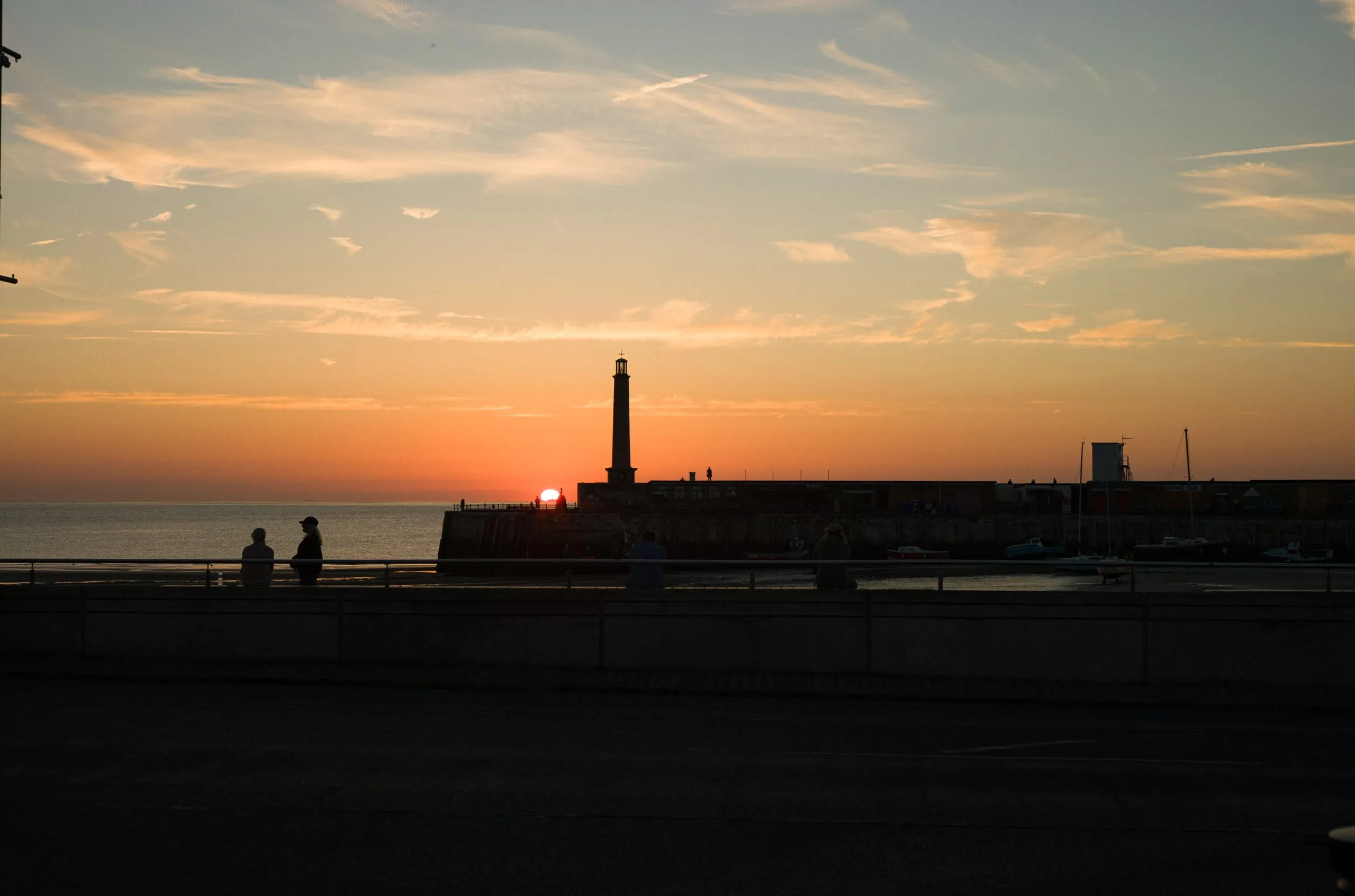 A woman stands next to the harbour lighthouse