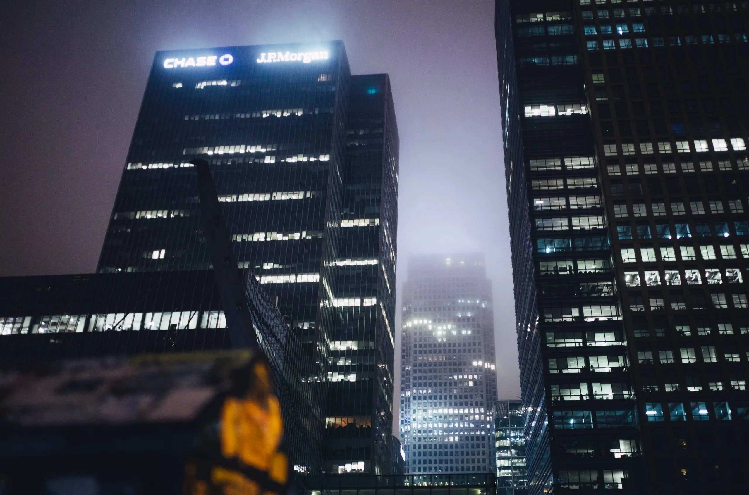 Office towers at night in mist, including the Chase and J.P. Morgan buildings, Canary Wharf